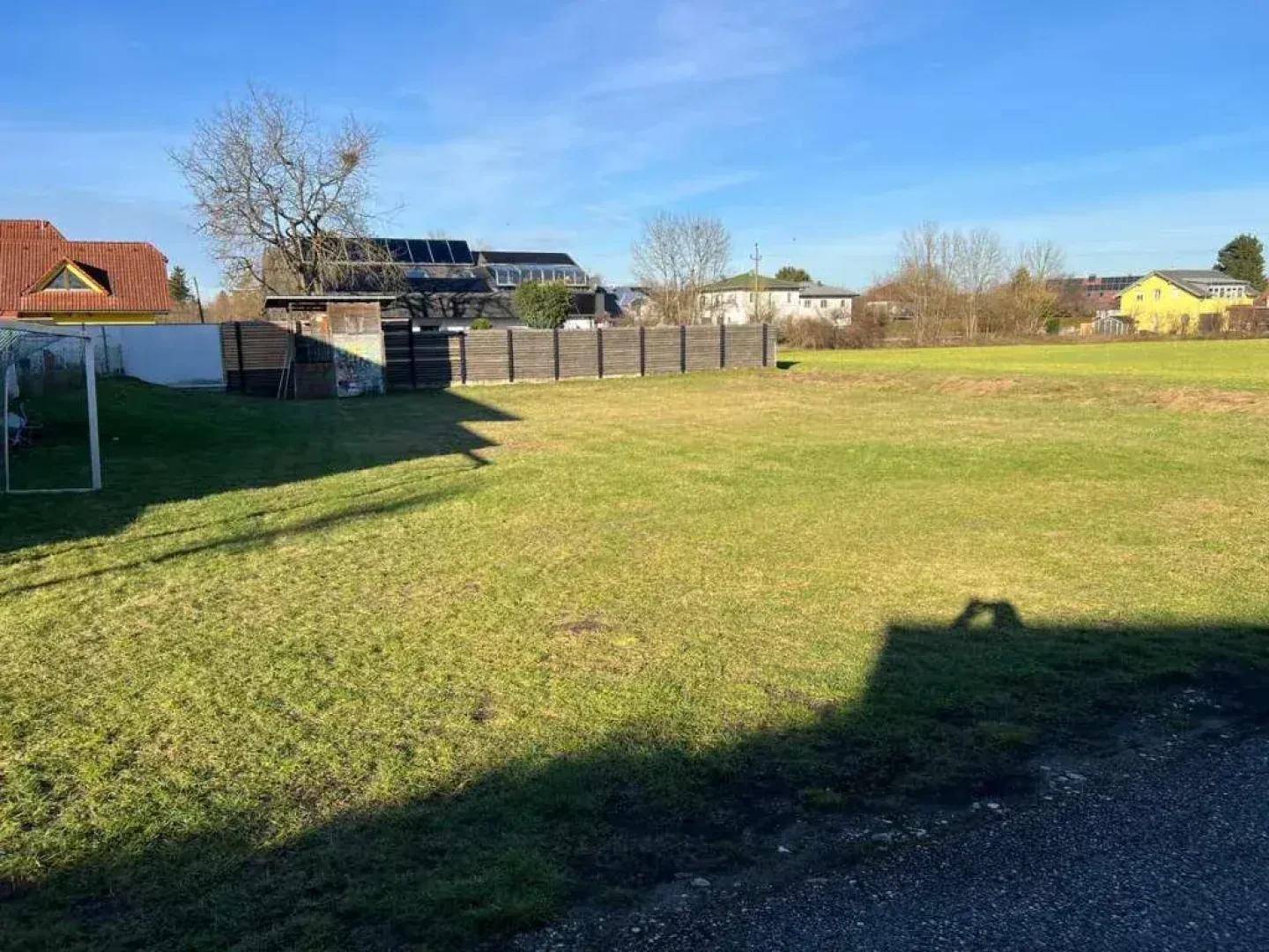 Weitläufige Grünfläche mit Fußballtor und Blick auf benachbarte Gebäude an einem sonnigen Tag.