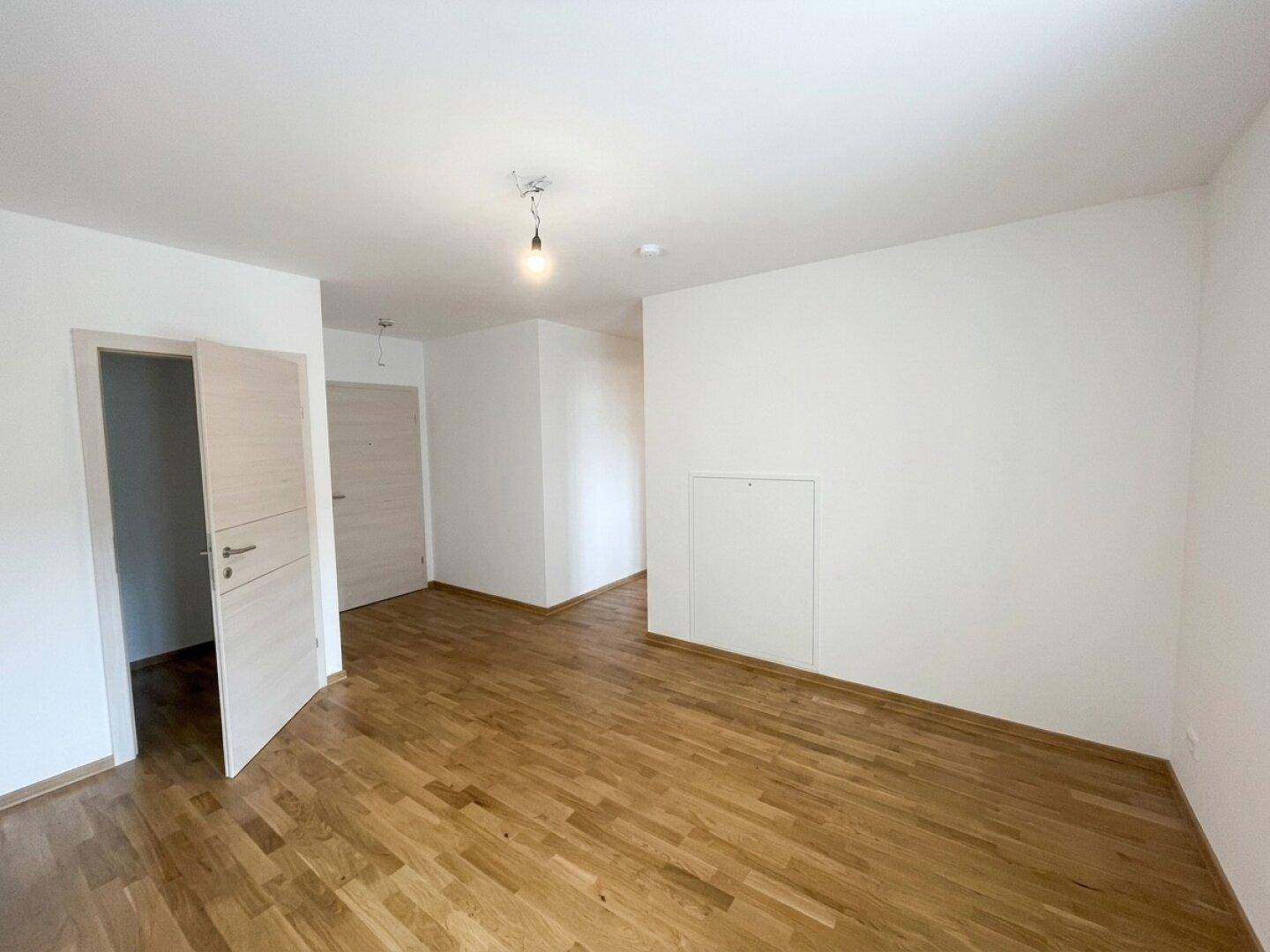 Heller, leerer Raum mit Parkettboden und weißen Wänden, bereit zum Einzug.