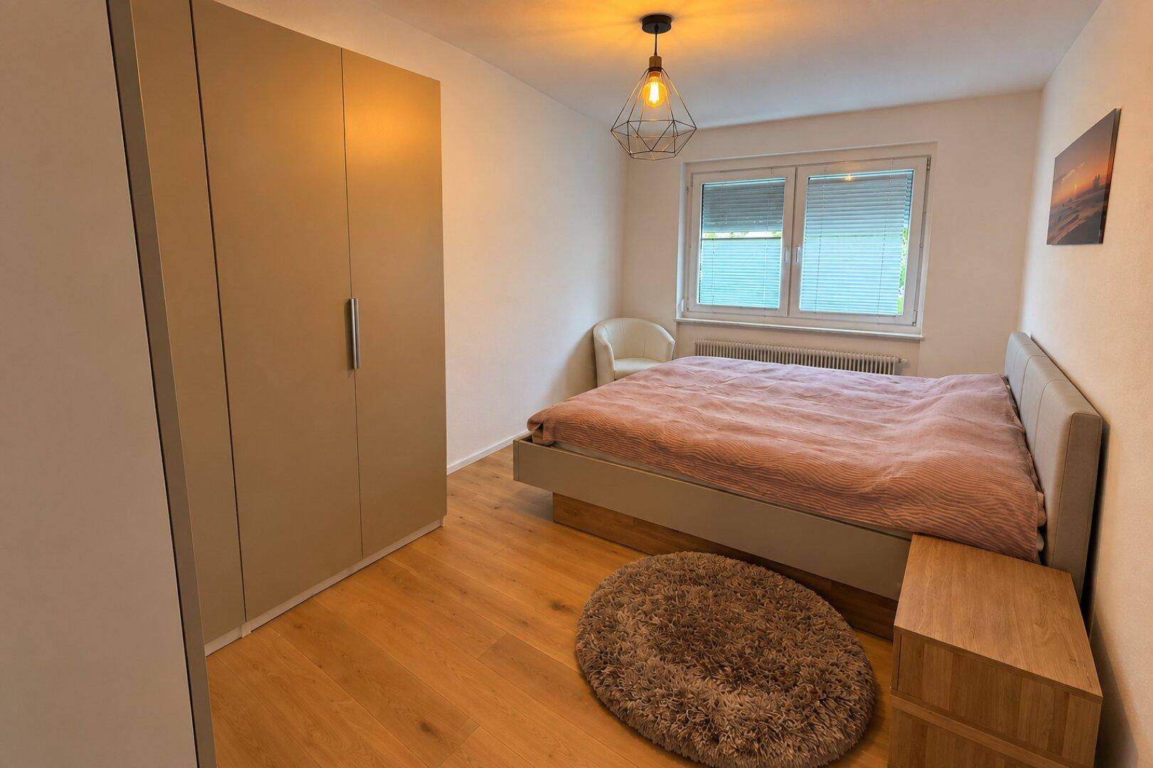 Gemütliches Schlafzimmer mit Holzboden, großem Kleiderschrank und Fenster.