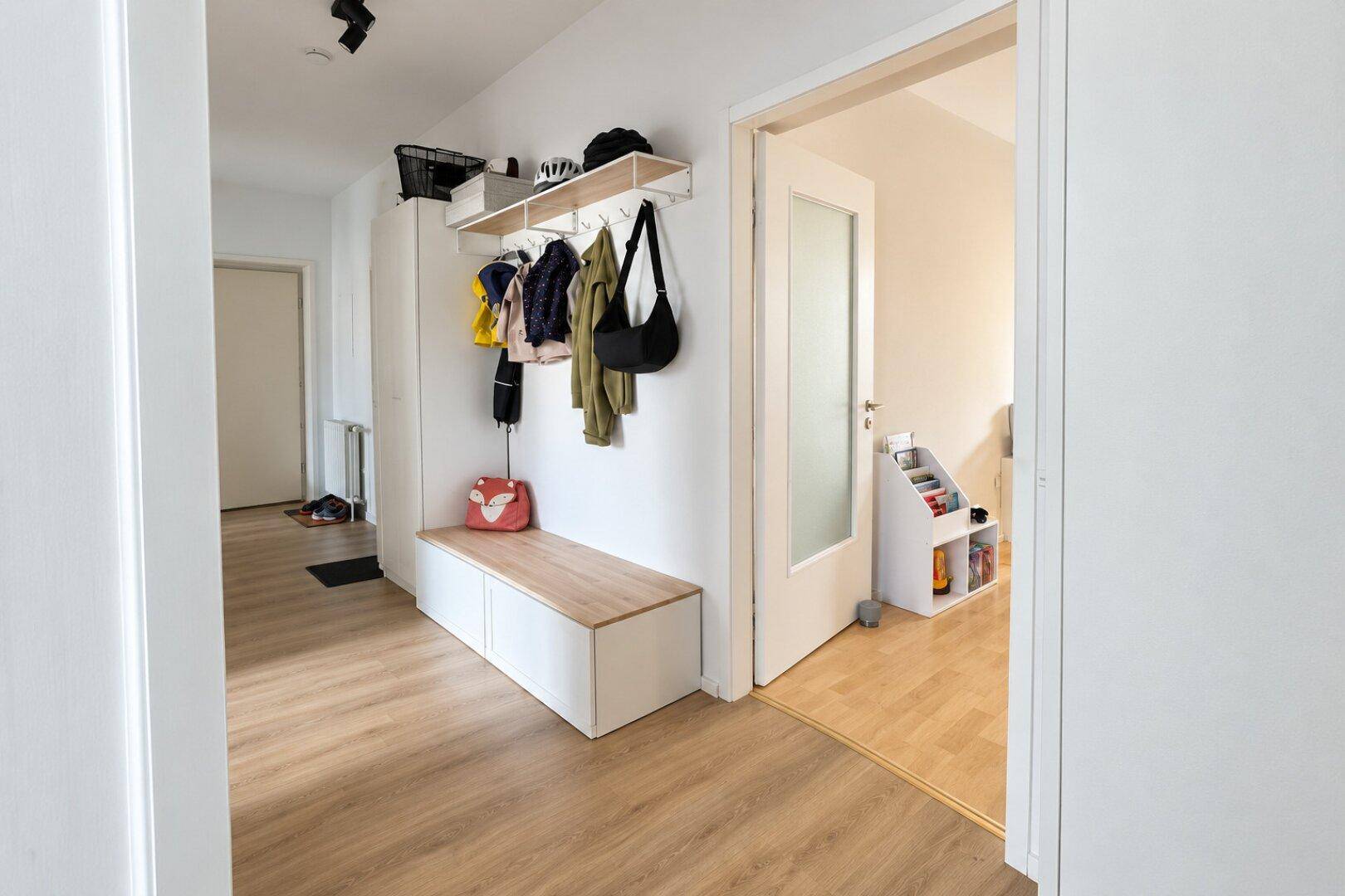 Eingangsbereich mit Garderobe, Sitzbank und Zugang zu weiteren Räumen.