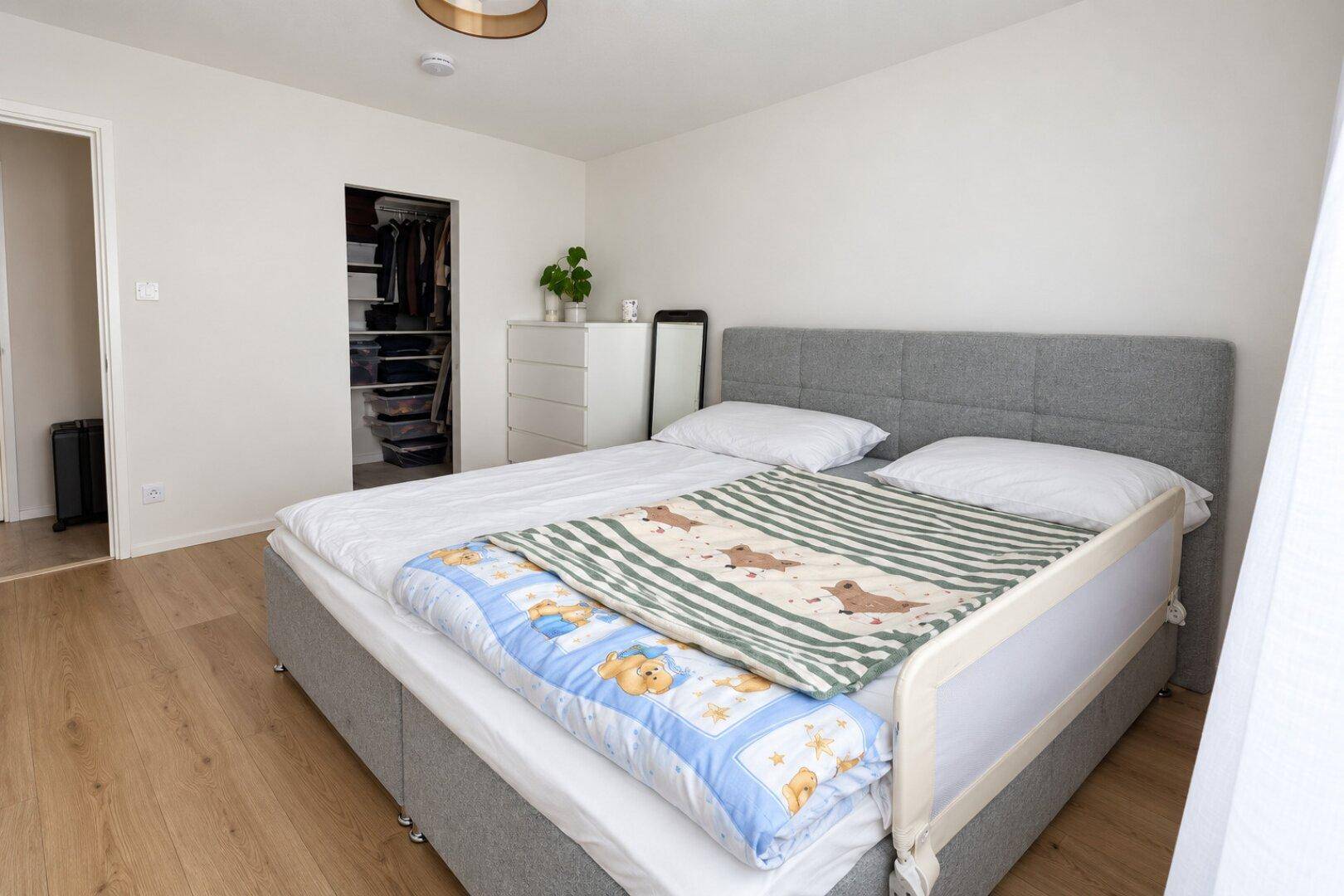 Schlafzimmer mit Doppelbett, Holzfußboden und begehbarem Kleiderschrank.