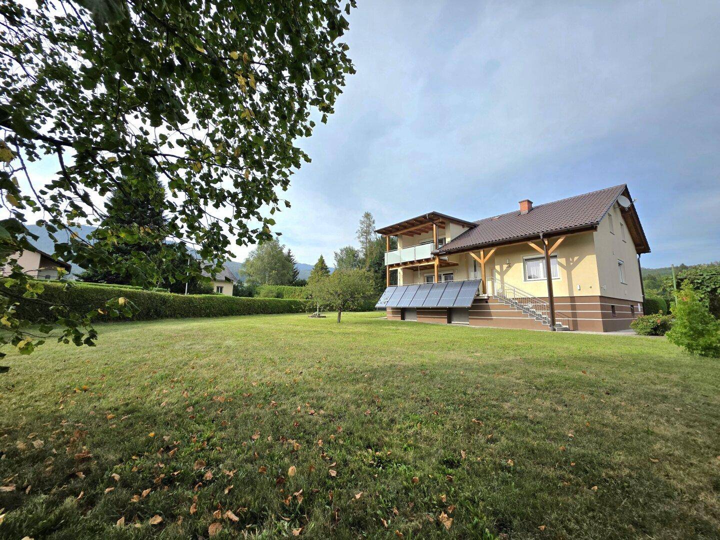Großzügiger Gartenbereich mit Rasenfläche und Blick auf das Haus mit Solaranlage.