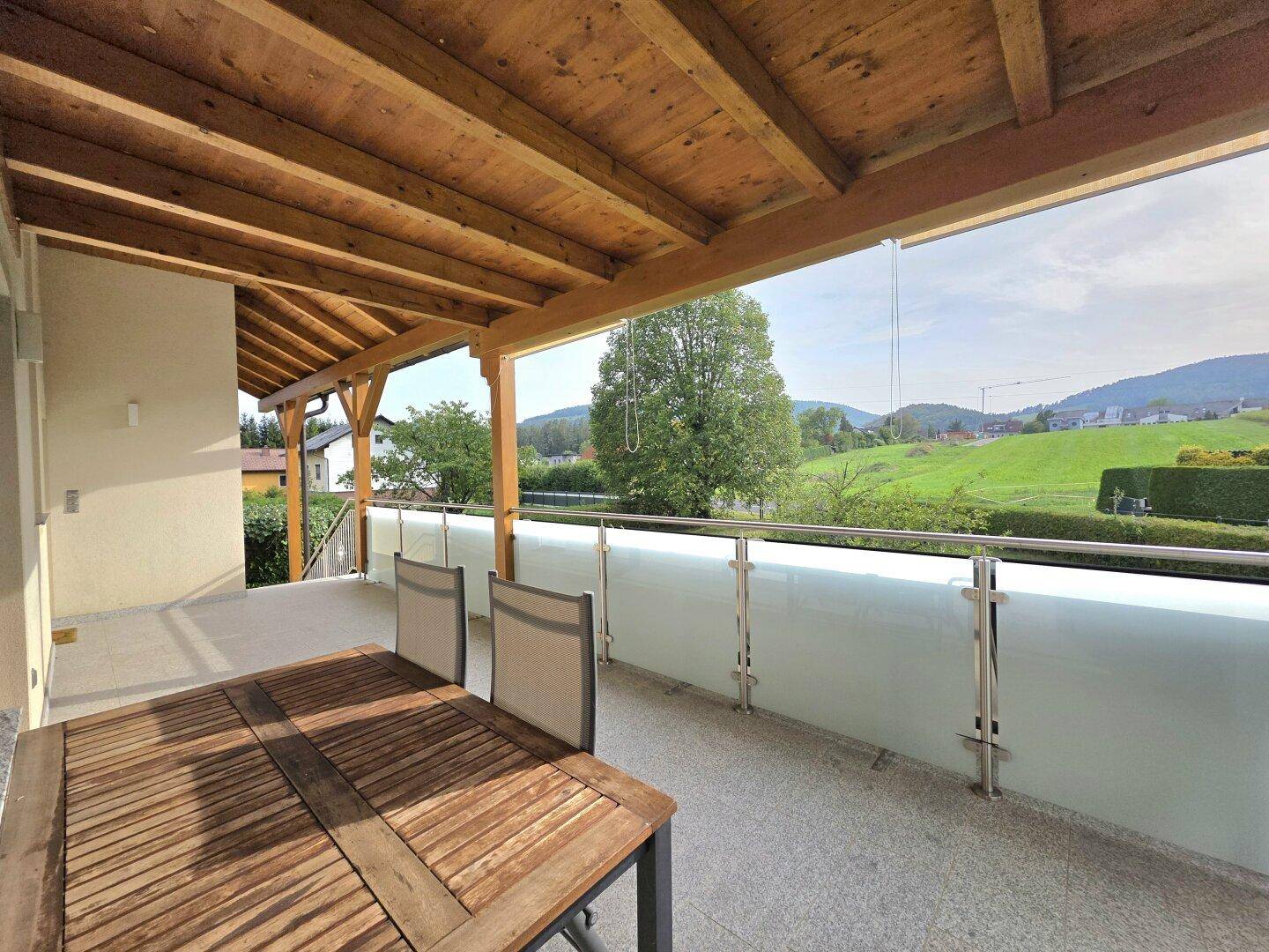 Überdachte Terrasse mit Holzdach und Glasgeländer, ideal für entspannte Stunden im Freien.
