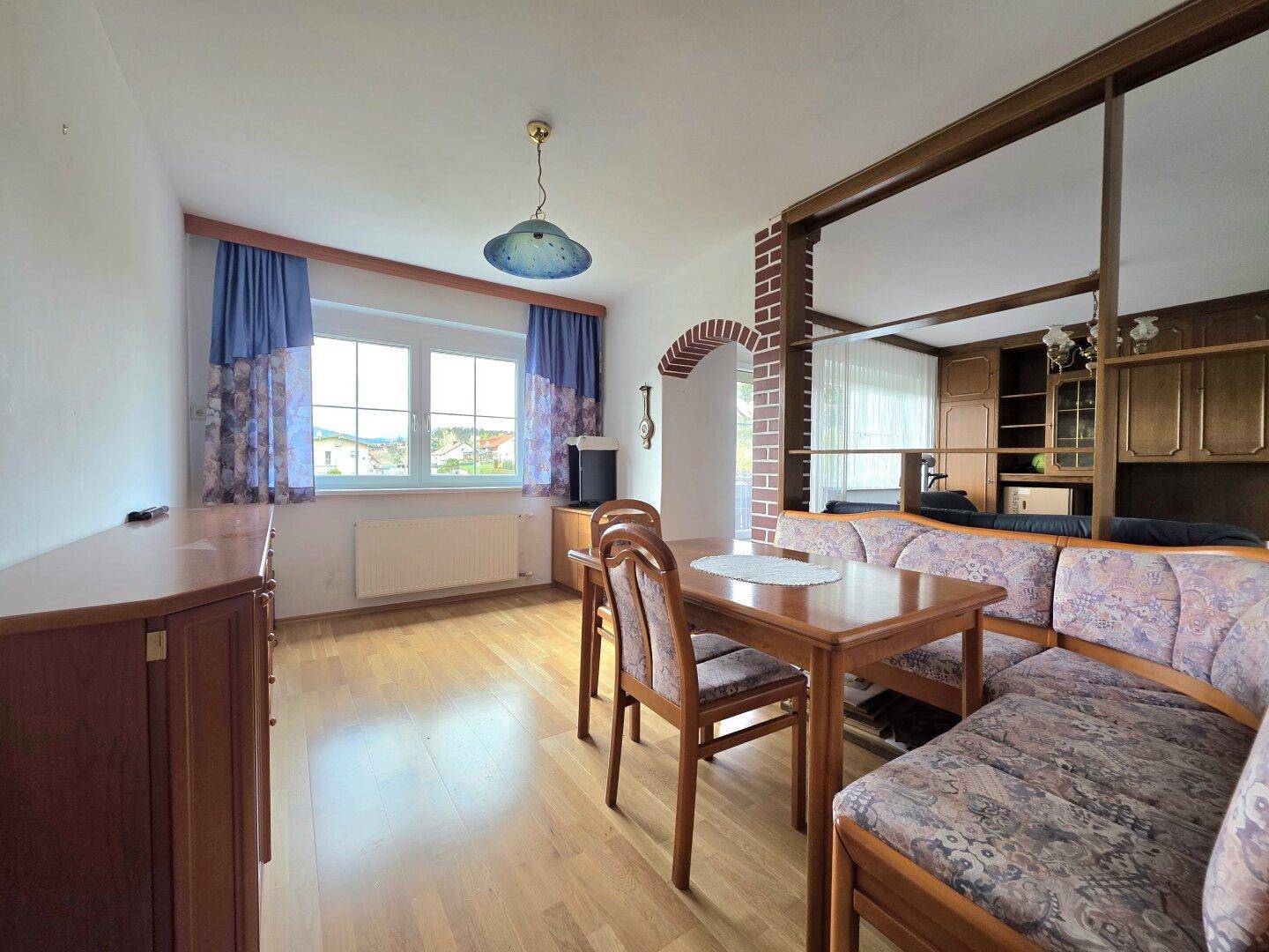 Wohn- und Essbereich mit Holzboden, traditionellen Möbeln und einem Fenster mit Weitblick.