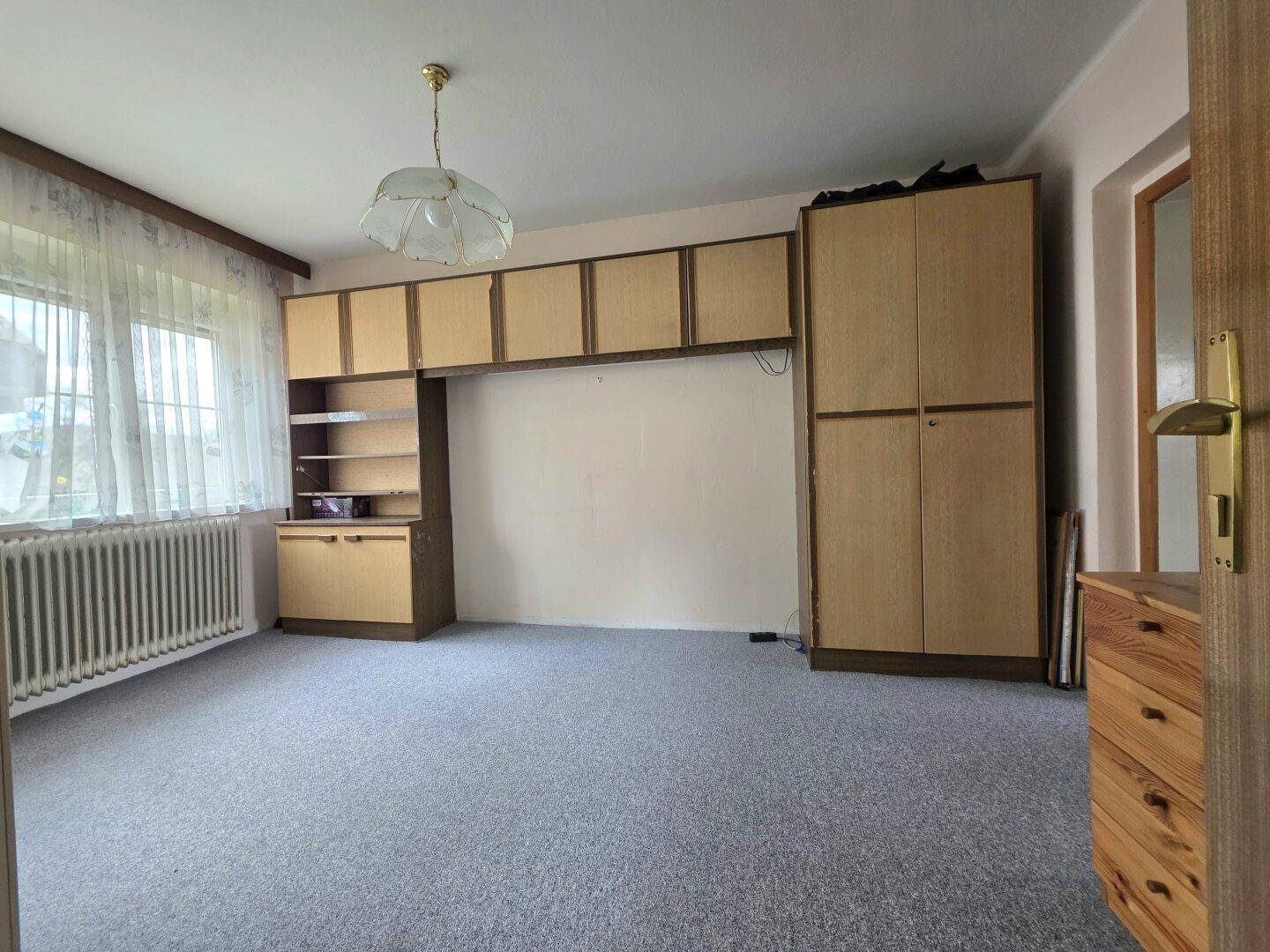 Geräumiges Schlafzimmer mit Teppichboden, Einbauschränken und einem großen Fenster.