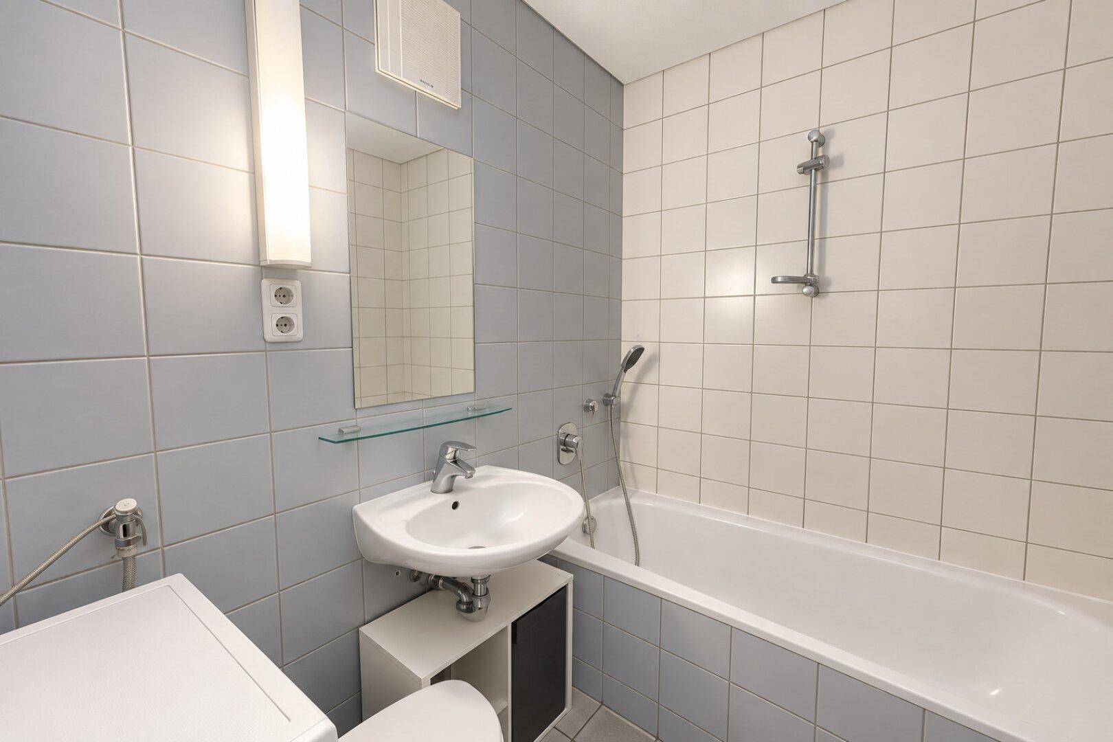 Helles Badezimmer mit blauen und weißen Fliesen, Badewanne und Waschbecken.