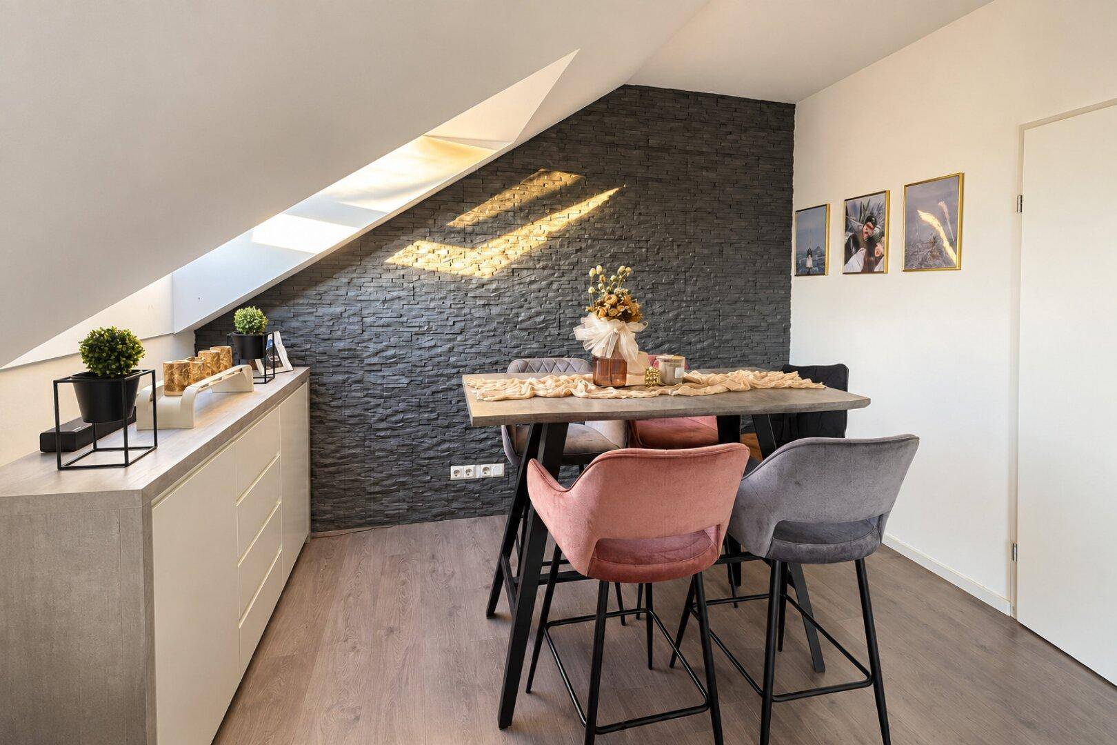 Moderner Essbereich mit Steinwand, Dachschräge und stilvollen Barhockern.