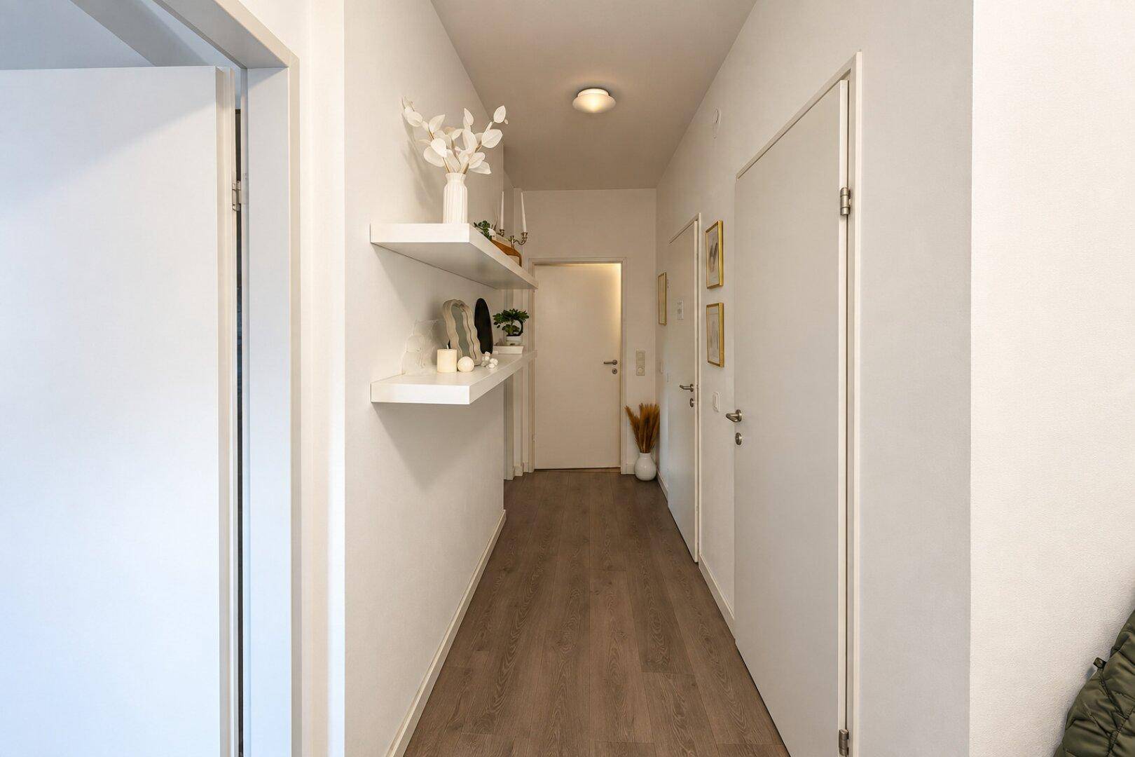Heller Flur mit modernem Laminatboden und dekorativen Wandregalen.