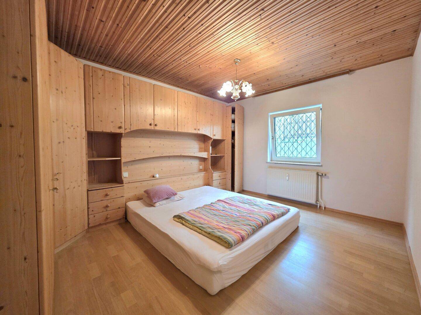 Schlafzimmer mit Holztäfelung an Decke und Wänden, integrierten Schränken und Holzboden.