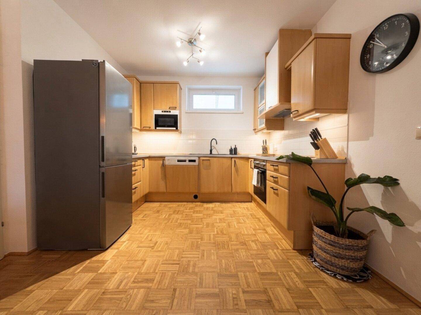 Funktionale Küche mit Holzfronten, Parkettboden und modernen Einbaugeräten.