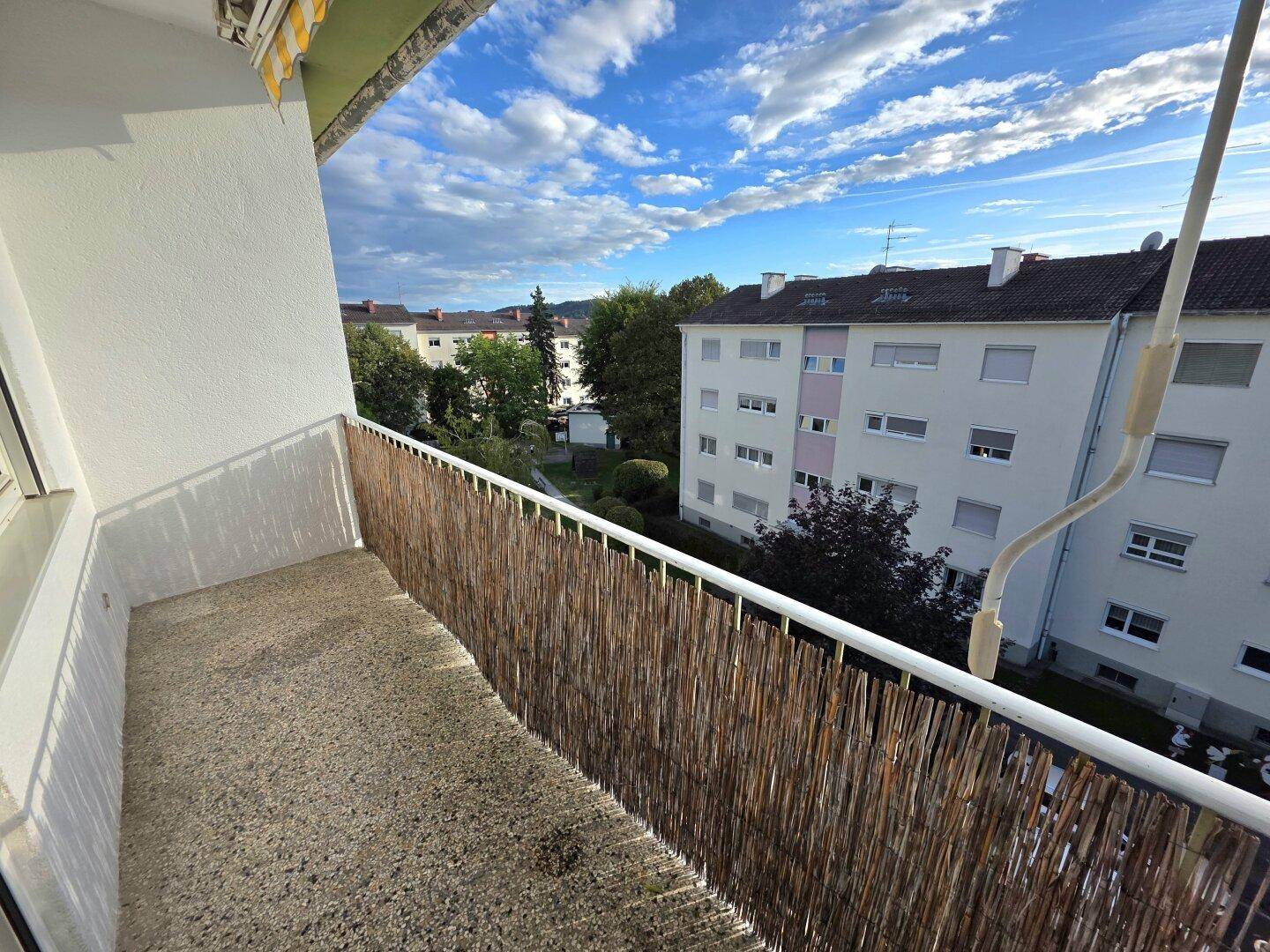 Balkon mit Bambusverkleidung und Blick auf die umliegenden Wohngebäude und Grünflächen.
