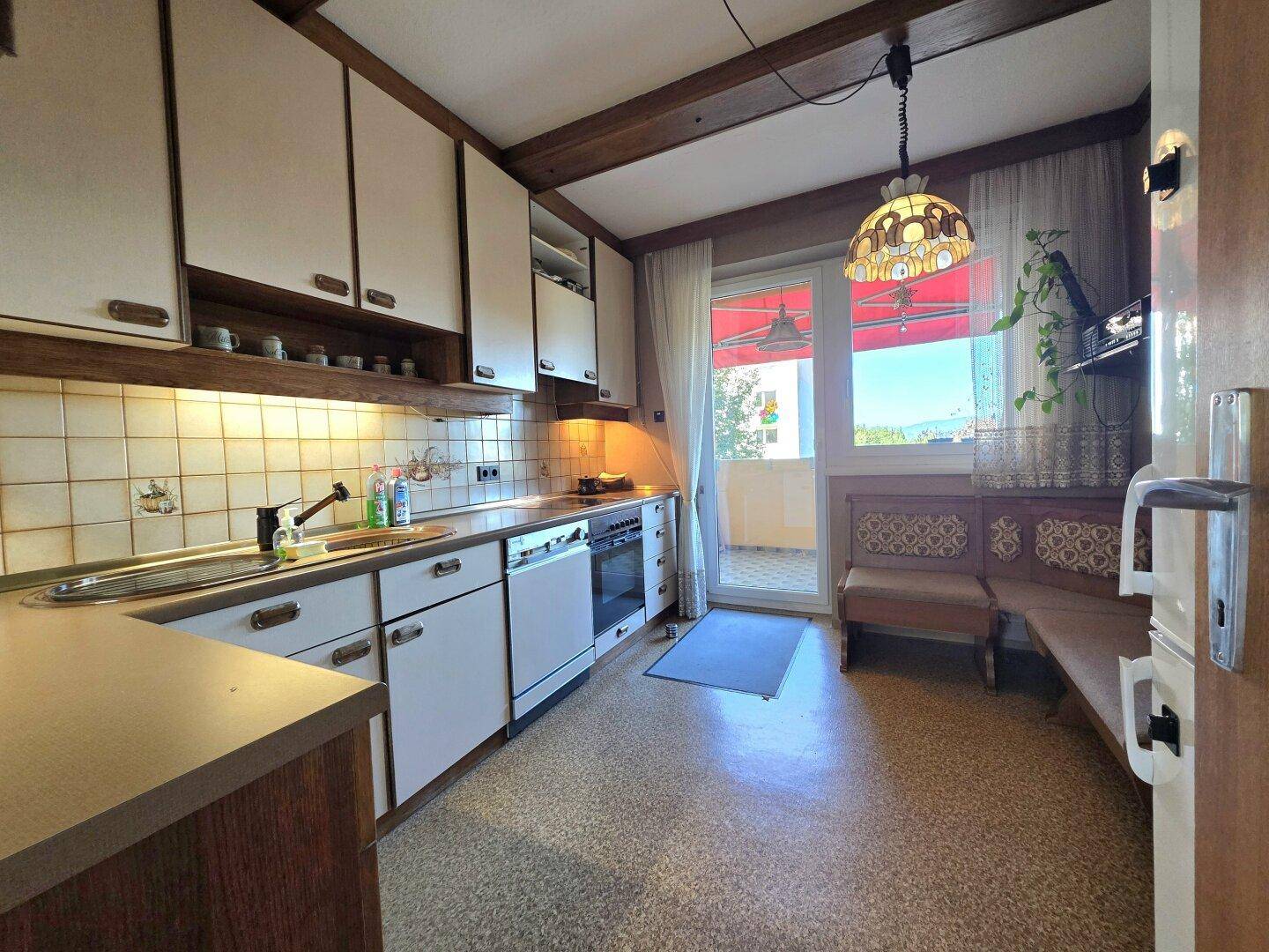 Funktionale Küche mit Einbauschränken, Essbereich und Zugang zu einem Balkon.