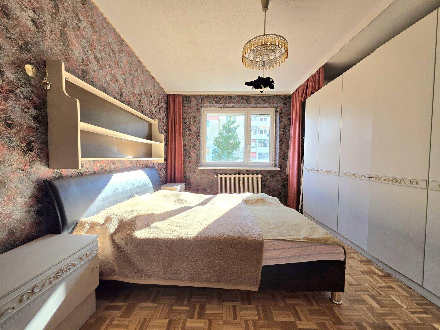 Schlafzimmer mit gemusterten Tapeten, großem Bett und Einbauschränken.