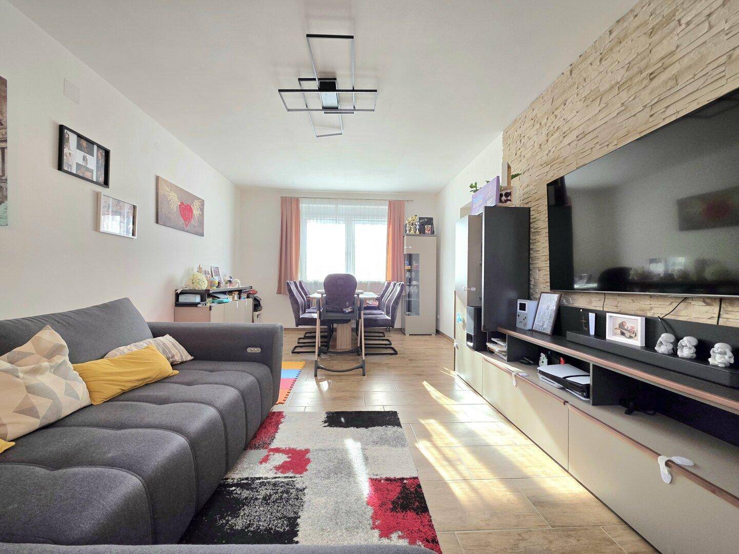 Geräumiger Wohn-Essbereich mit moderner Einrichtung, dekorativer Steinwand und Blick zum Essbereich.