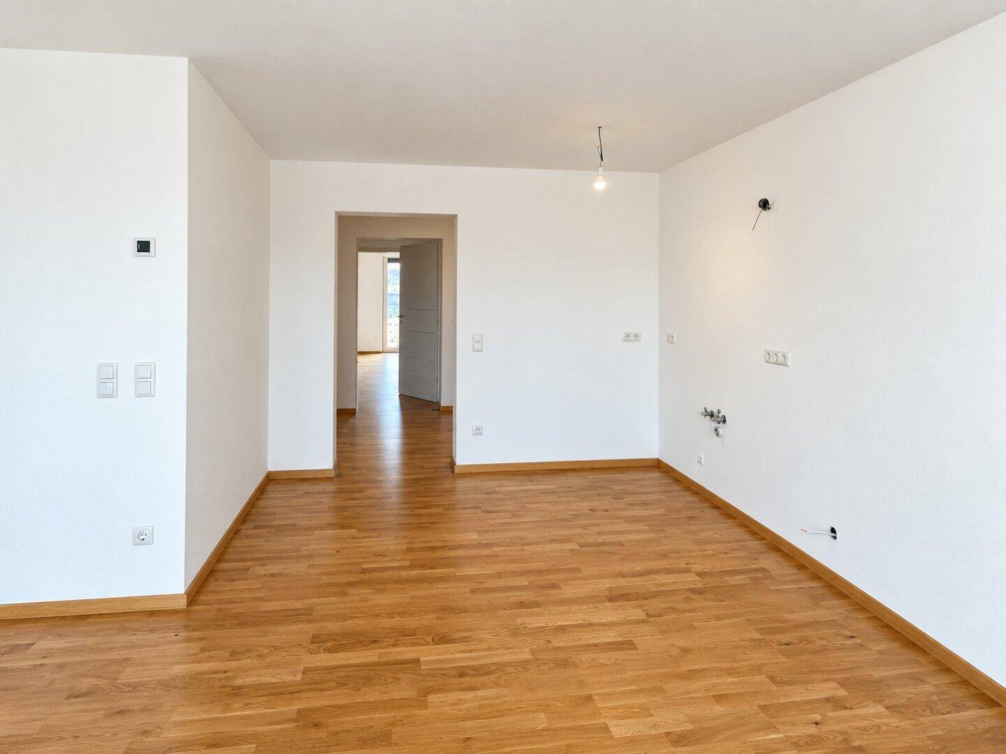 Heller Raum mit Parkettboden, vorbereitet für die Installation einer modernen Küche.