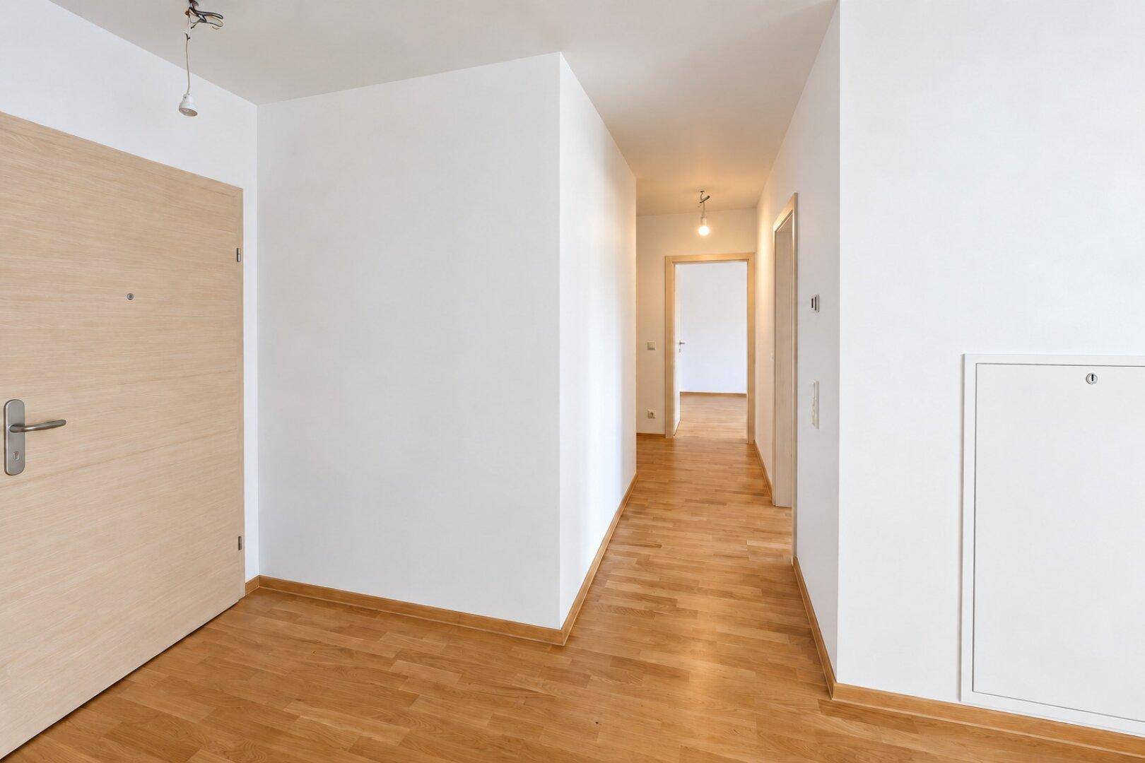 Heller Flur mit Parkettboden und mehreren Türen, der verschiedene Bereiche der Wohnung verbindet.