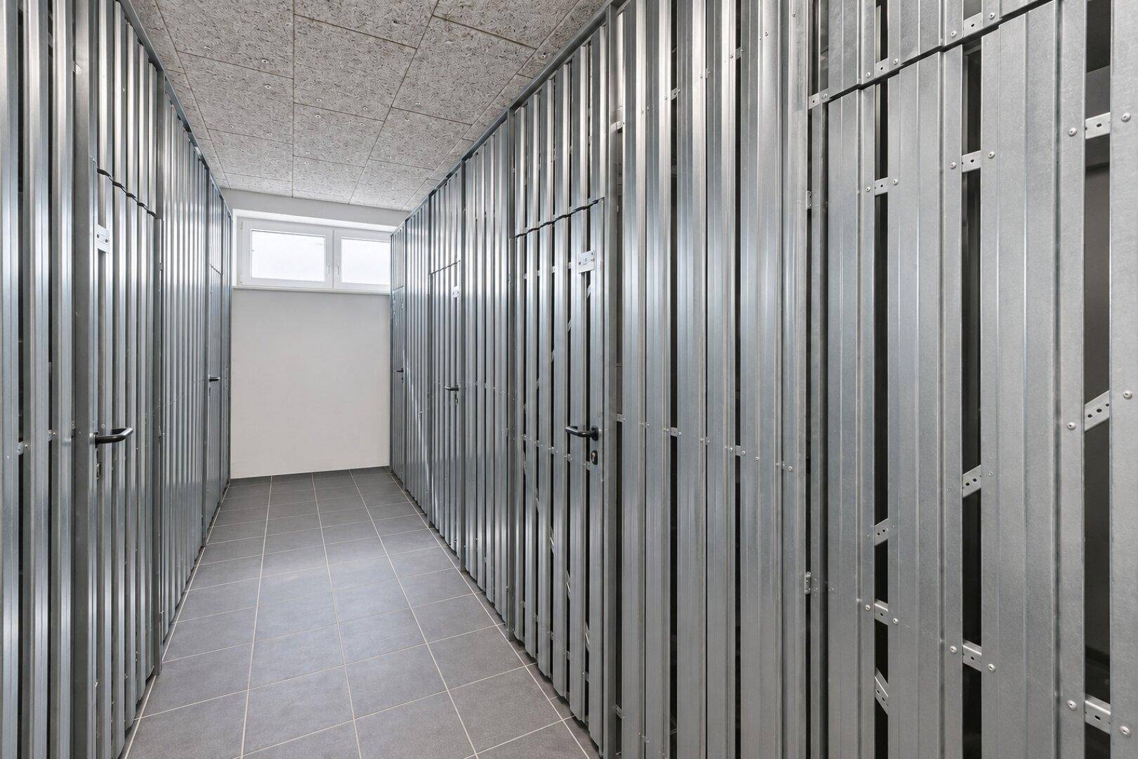 Kellerraum mit praktischen Metallabtrennungen für zusätzlichen Stauraum und einem kleinen Fenster.