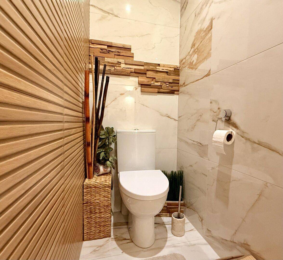 Stilvolles Gäste-WC mit modernen Fliesen, Holzdetails und Stand-WC.