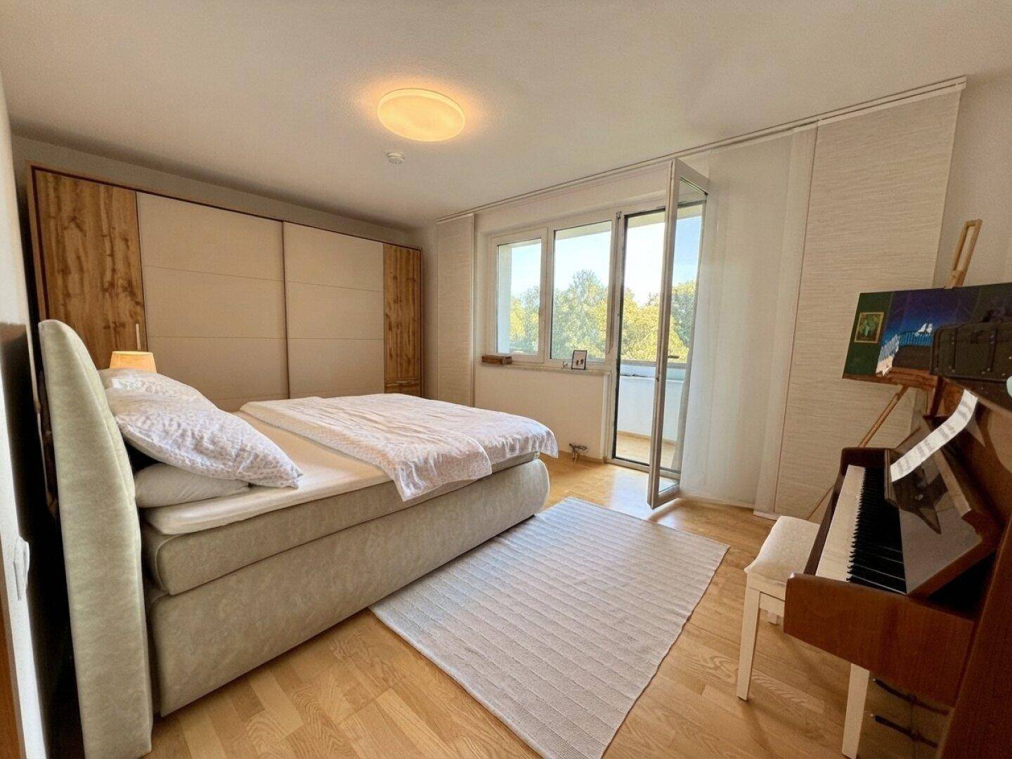 Geräumiges Schlafzimmer mit Doppelbett, Einbauschrank und Zugang zum Balkon.