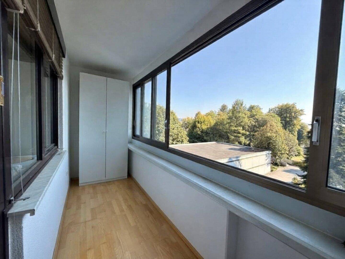 Verglaster Balkon mit weitem Blick ins Grüne und viel Tageslicht.