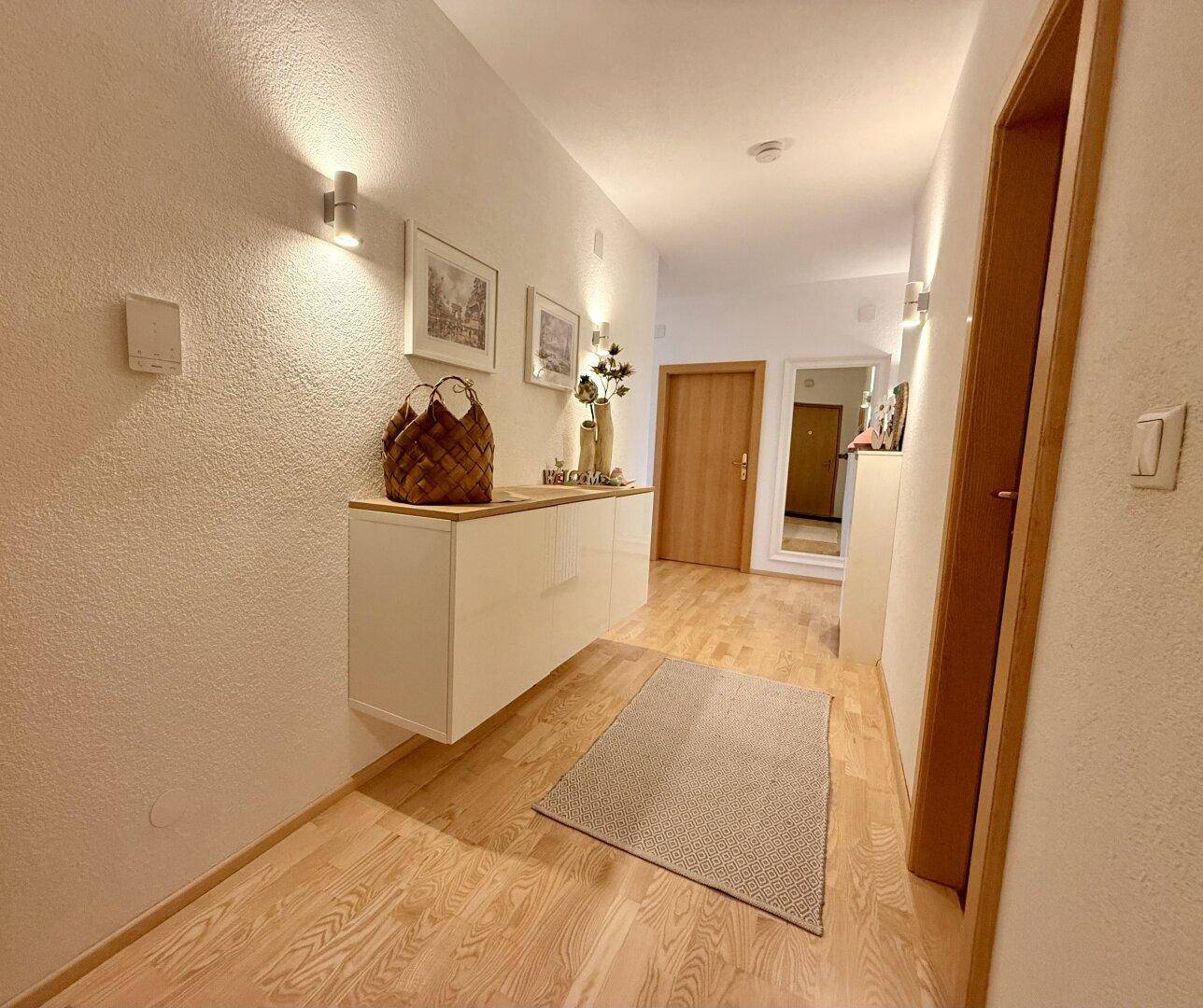 Heller Flur mit schwebendem Schrank, Spiegel und hellem Parkettboden.