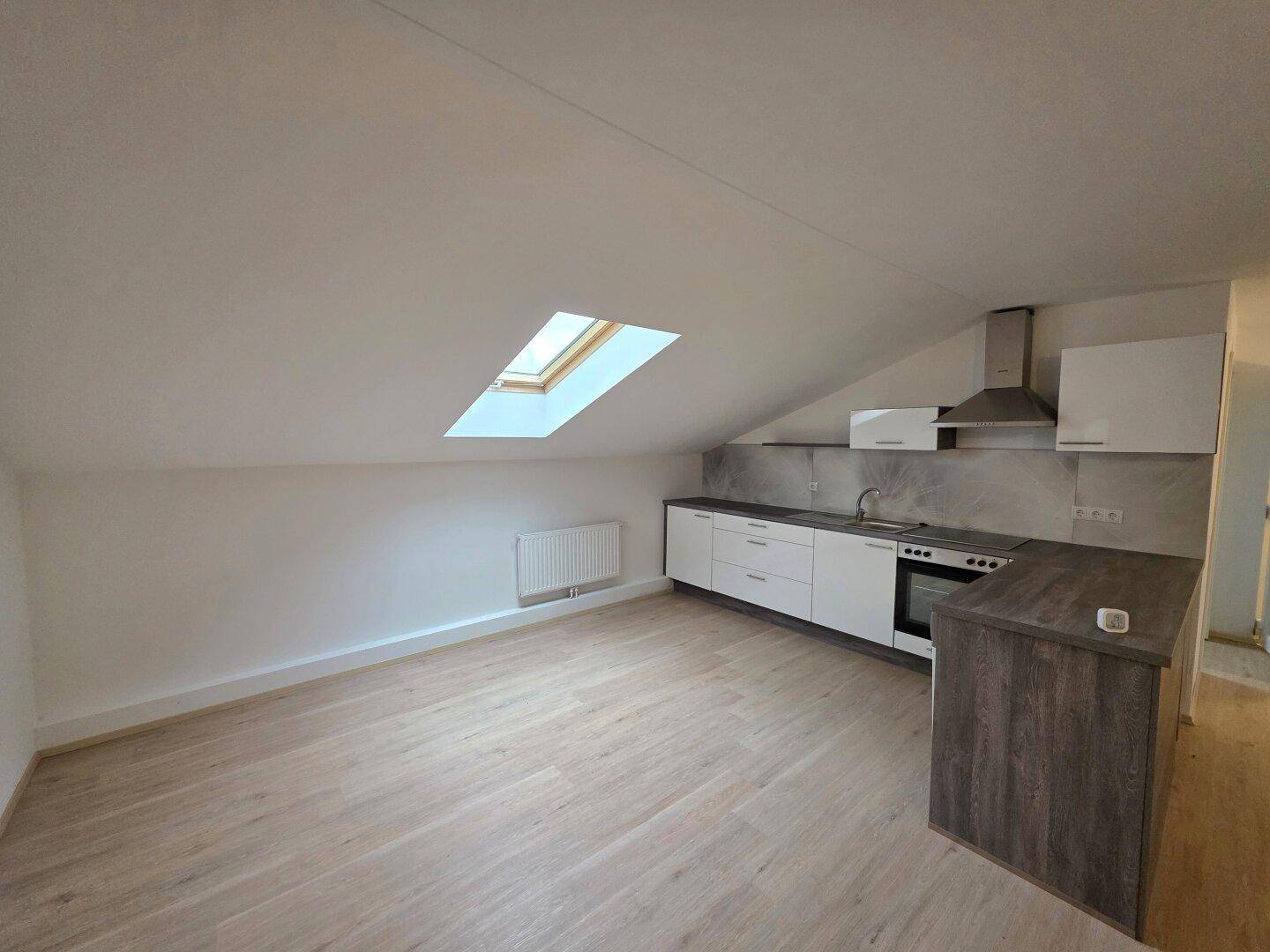 Dachgeschossküche mit Schrägdach, Dachfenster, moderner Einrichtung und hellem Laminatboden.