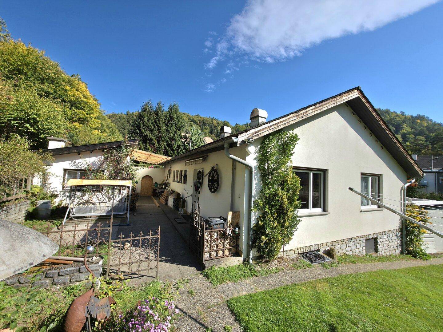 Fassade des Hauses mit einem gepflasterten Weg, dekorativen Elementen und üppiger Begrünung.