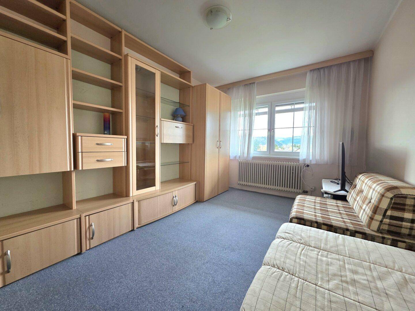 Schlafzimmer mit Schlafcouch, Holzregalen und Fenster mit weitem Ausblick.