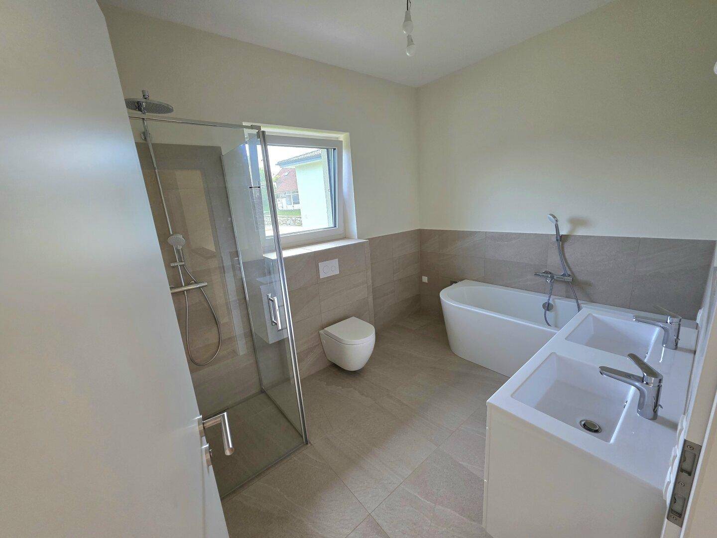 Geräumiges Badezimmer mit Dusche, Badewanne und Doppelwaschbecken, noch in Fertigstellung, aber modern.