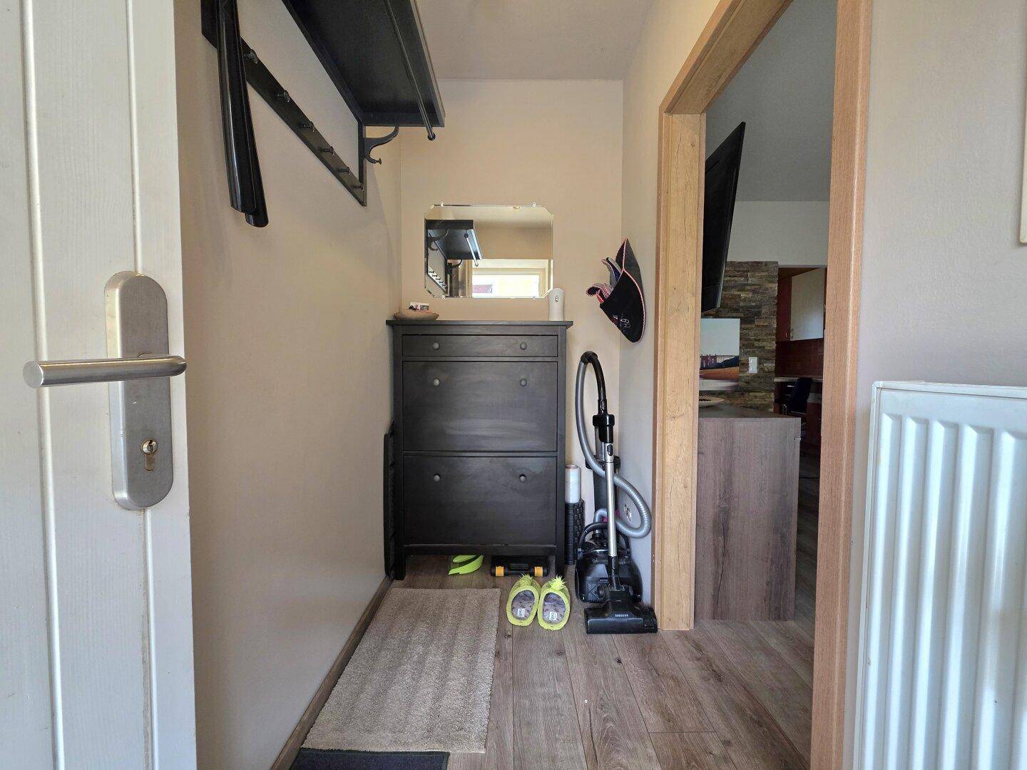 Eingangsbereich mit Garderobe, Schuhschrank und Holzboden.