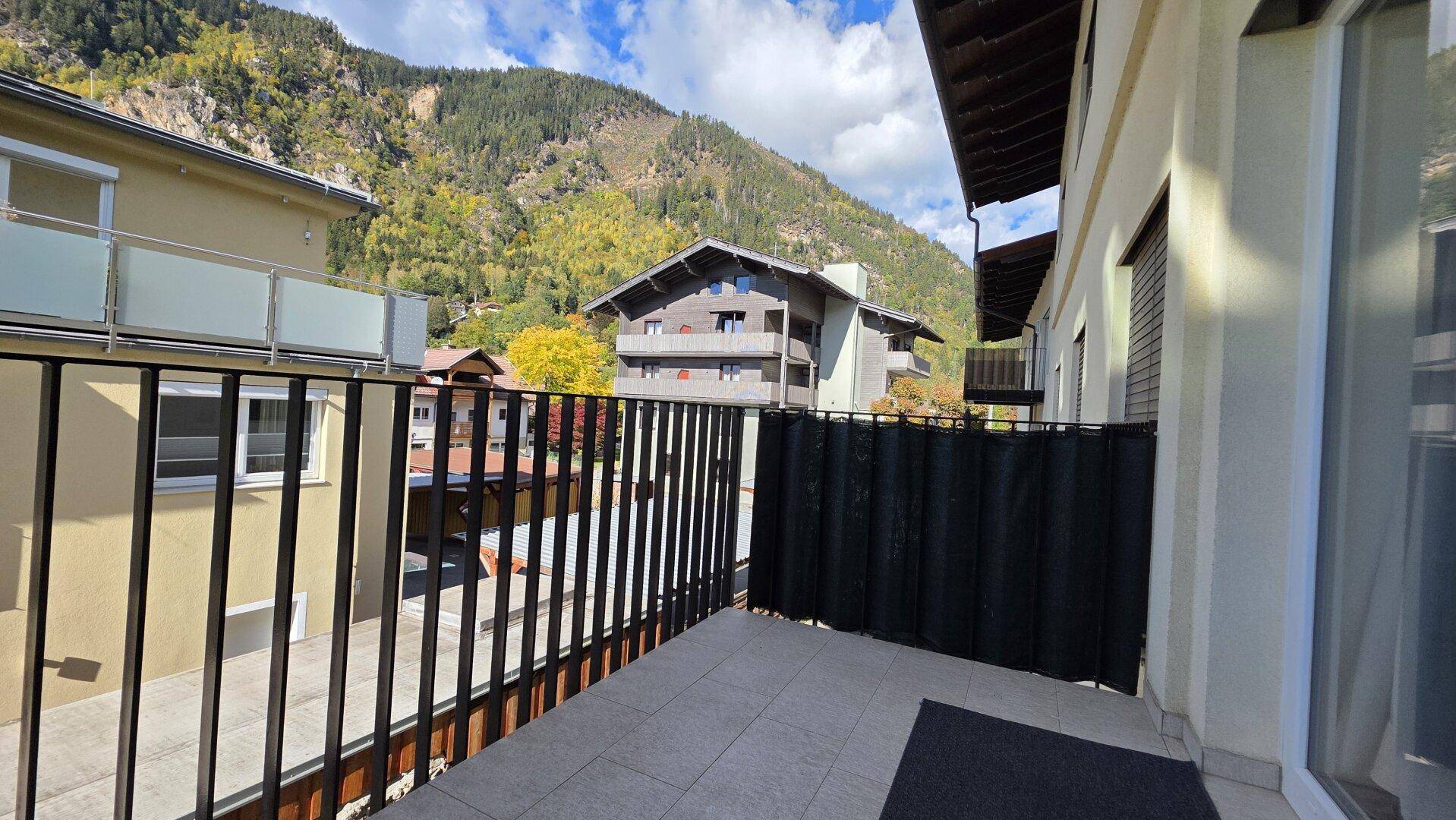 Balkon mit Bergblick und Aussicht auf die umliegende Bebauung und Natur.
