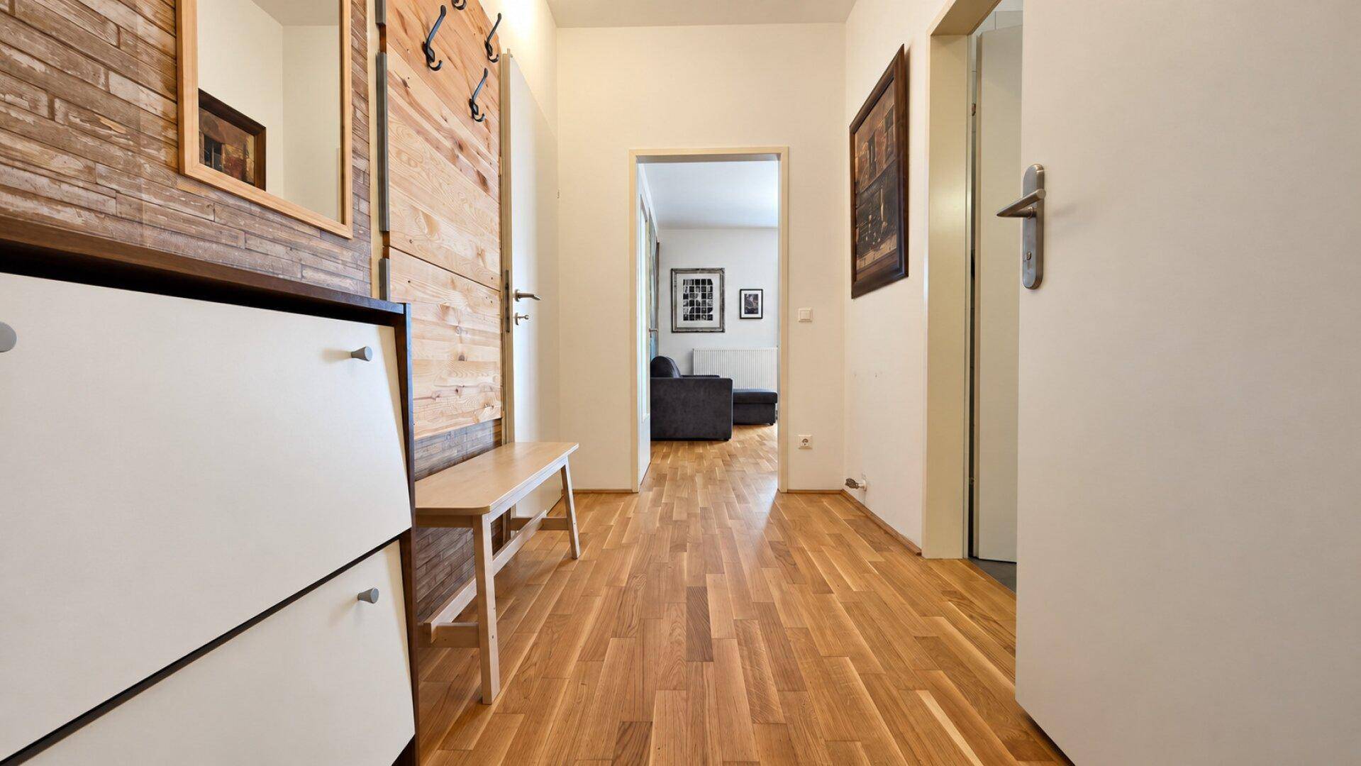 Heller Flur mit Holzakzenten, Schuhschrank und Zugang zu den weiteren Räumen.