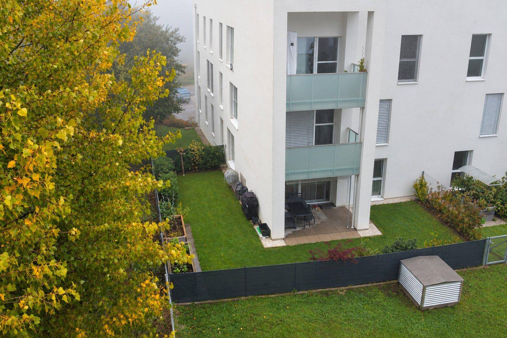 Vogelperspektive des Apartmentgebäudes mit privatem Garten, Terrasse und Hochbeeten.