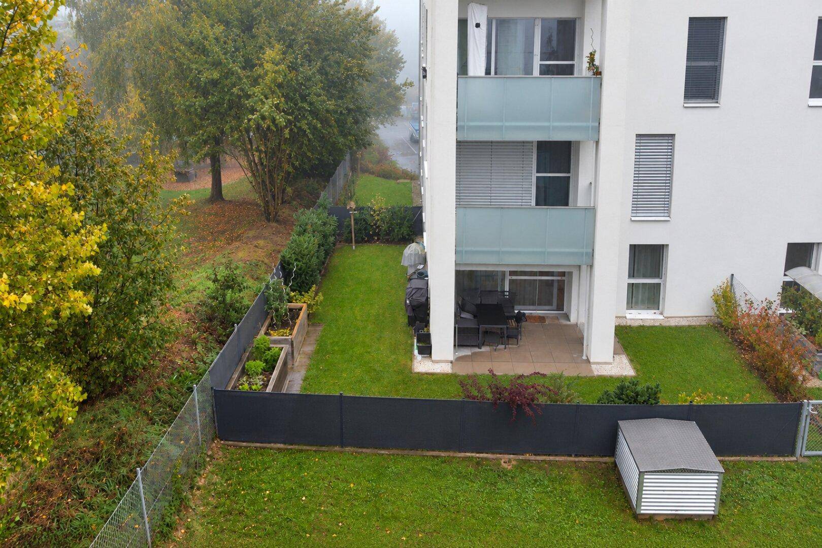 Übersicht des Apartmentgebäudes mit privatem Garten, Terrasse, Hochbeeten und Gartenschuppen.
