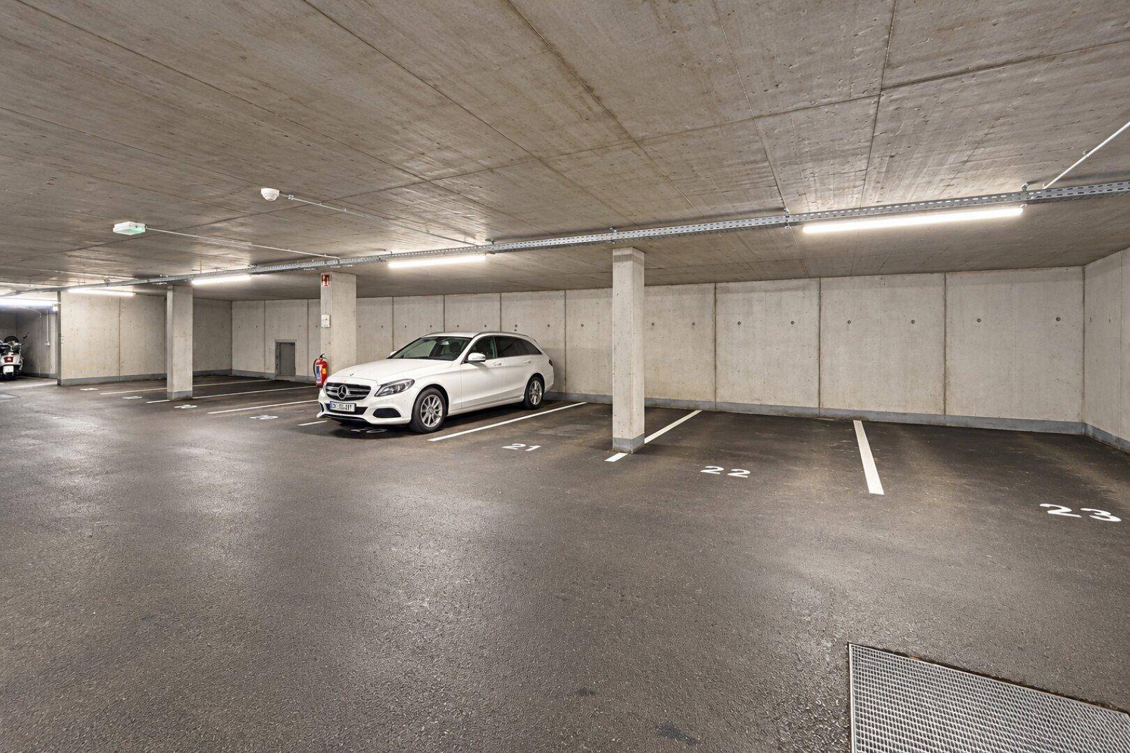 Tiefgarage mit ausreichend Parkplätzen und moderner Beleuchtung, ein weißes Auto parkt.