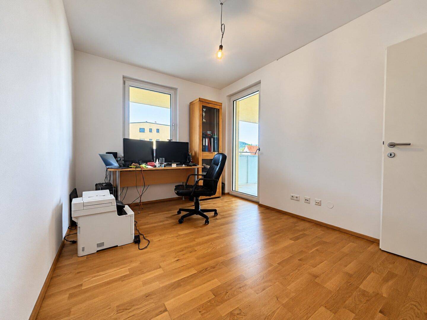 Funktionales Zimmer, ideal als Büro oder Gästezimmer, mit Parkettboden und Balkonzugang.