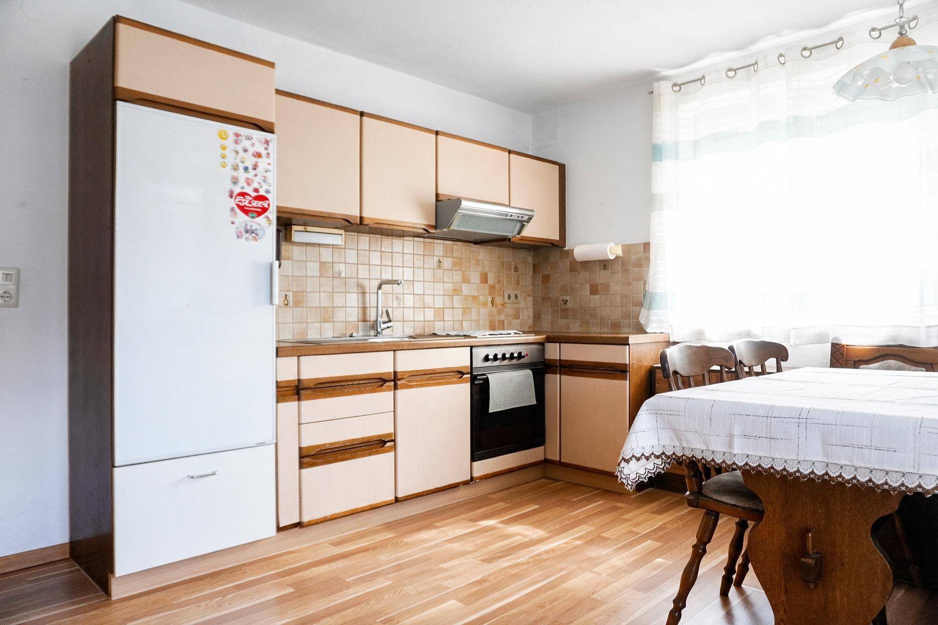Funktionale Küche mit hellen Schränken, Essbereich und Kühlschrank, praktisch für den Alltag.