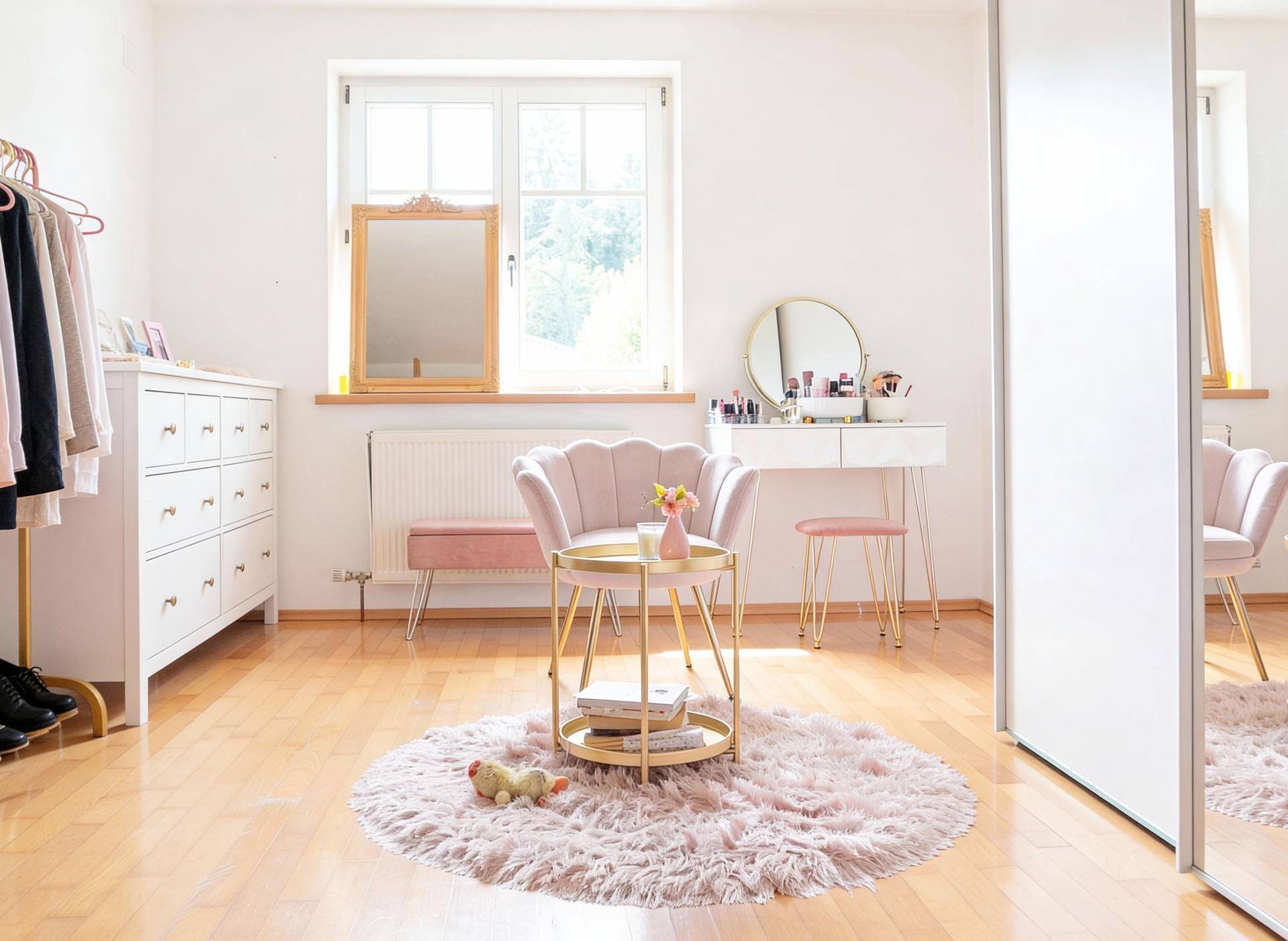 Helles Schlafzimmer mit Holzboden, Schminktisch und einem großen Fenster.