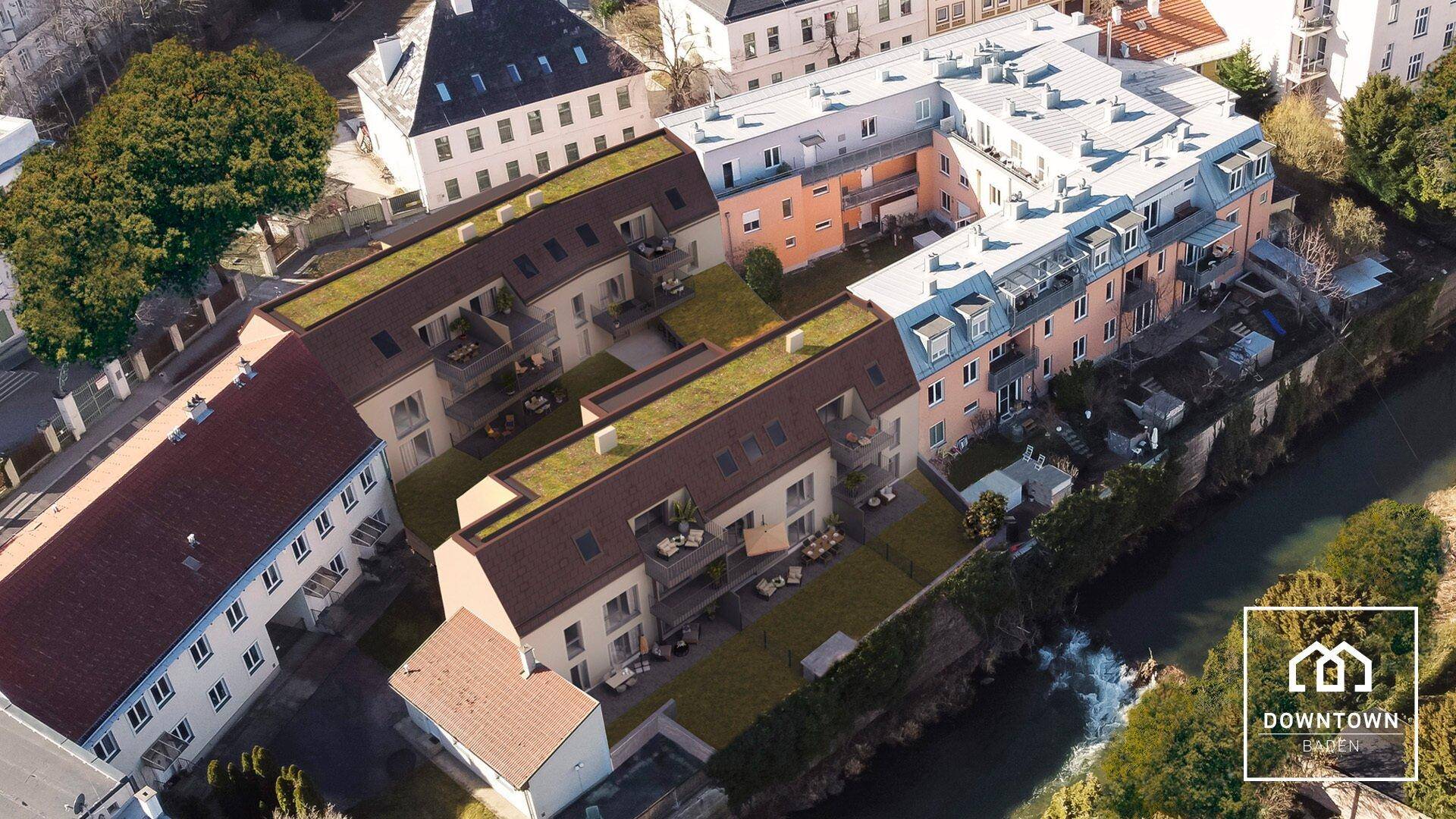 Luftaufnahme eines modernen Wohnkomplexes mit begrünten Dächern und Flussnähe.