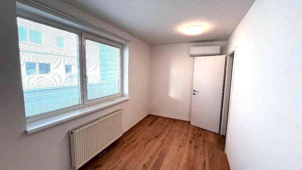 Helles Schlafzimmer mit Holzfußboden, Fenster mit Jalousien und einer Klimaanlage für Komfort.