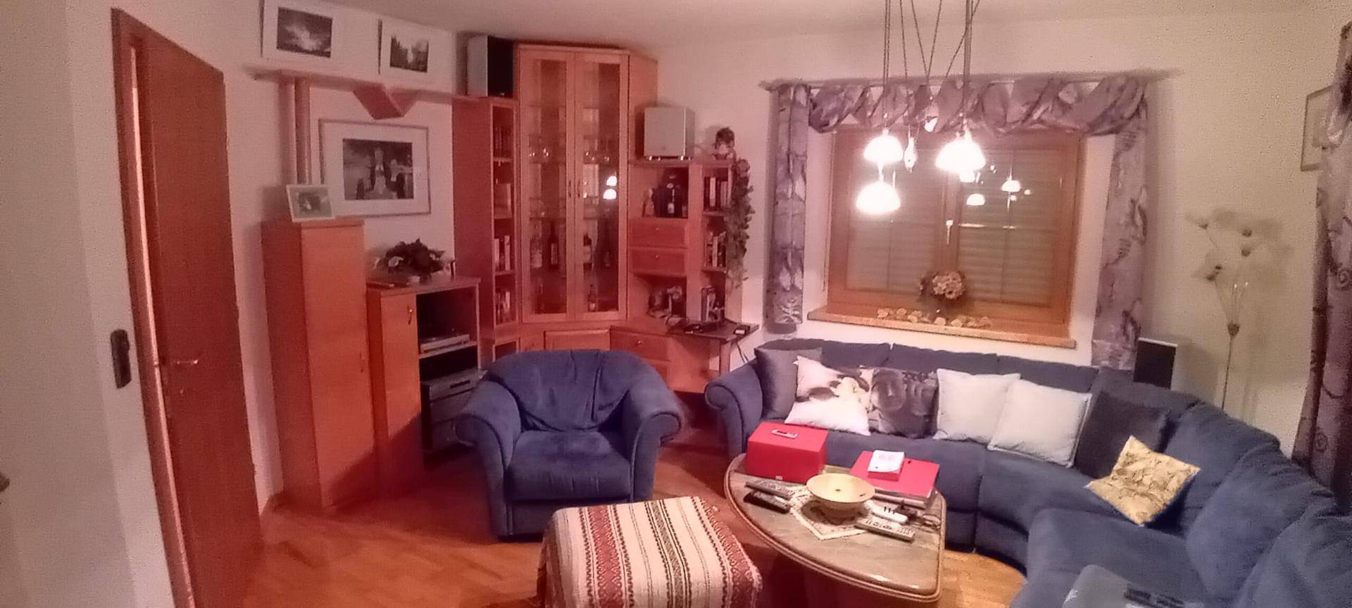 Gemütliches Wohnzimmer mit blauen Sofas, Holzmöbeln und einem großen Fenster.