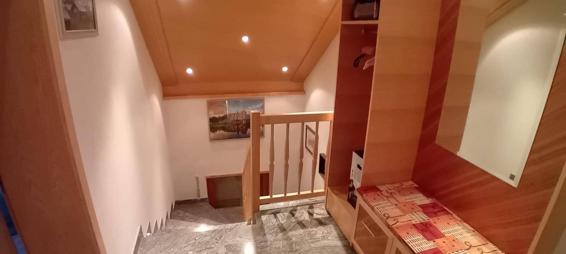 Treppenaufgang mit Holzvertäfelung und integrierten Schränken, der zu den oberen Etagen führt.