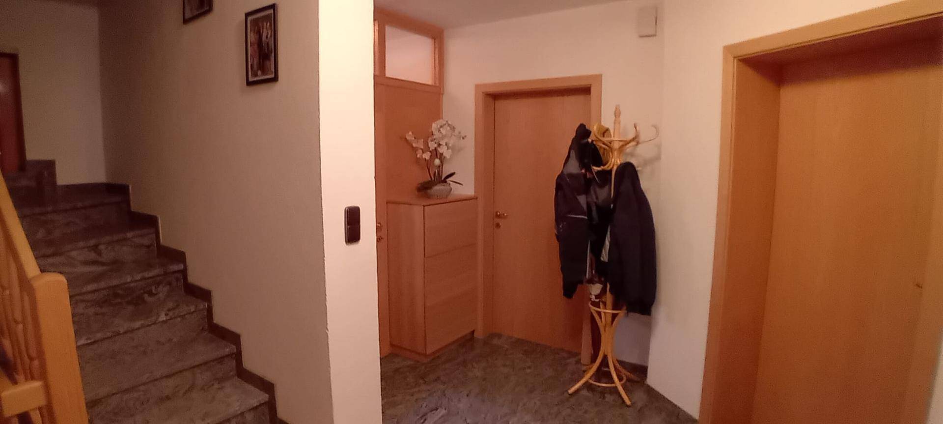 Heller Eingangsbereich mit Steintreppe und Garderobe, ausgestattet mit Holzmöbeln.