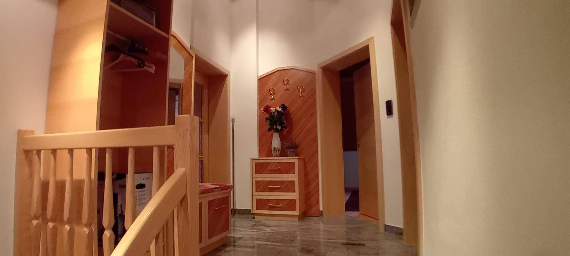 Heller Flur mit Holzmöbeln und Dekoration, der zu verschiedenen Räumen führt.