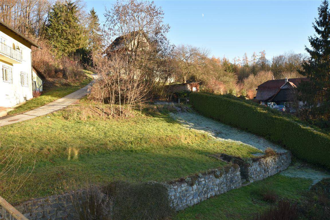 Hanglage mit gepflegtem Garten, Steinmauern und Hecken, umgeben von Bäumen und Natur.