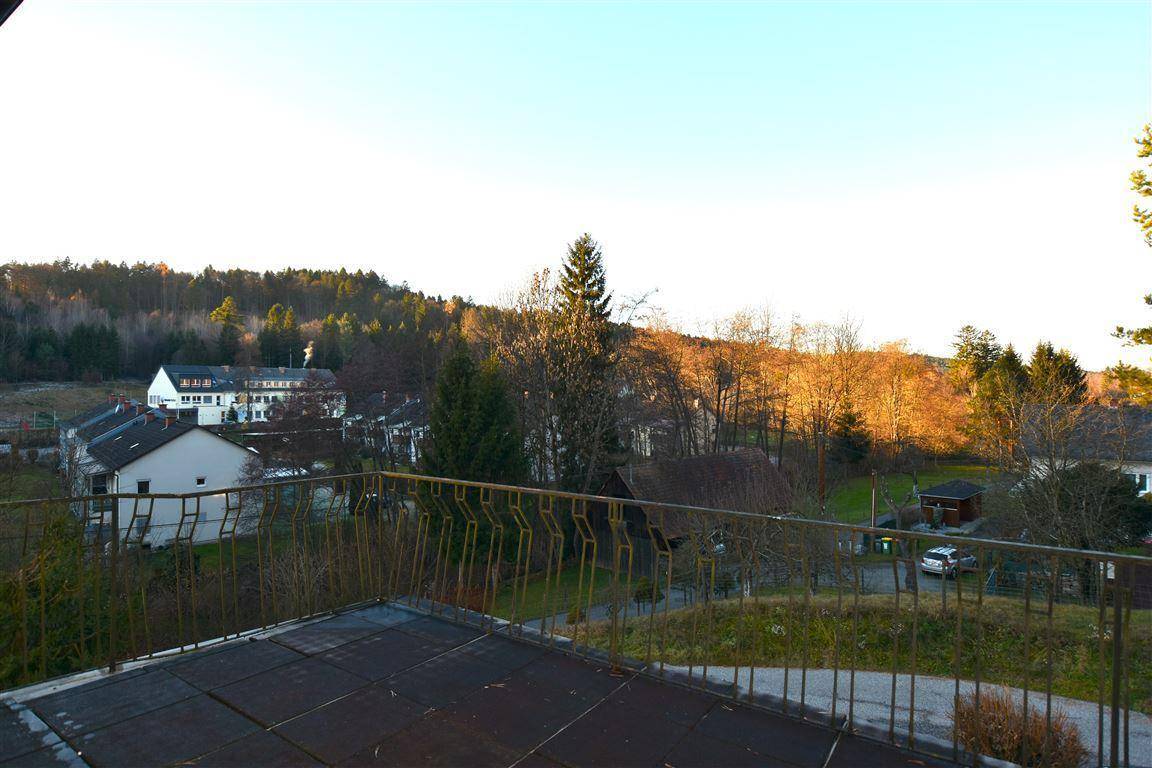 Balkon mit Metallgeländer und weitem Blick über die ländliche Umgebung und Dächer.
