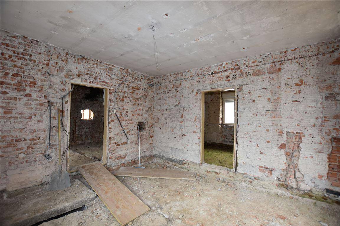 Innenraum in Abrisszustand mit freigelegten Ziegelwänden und Betonboden, bereit für umfassende Renovierung.