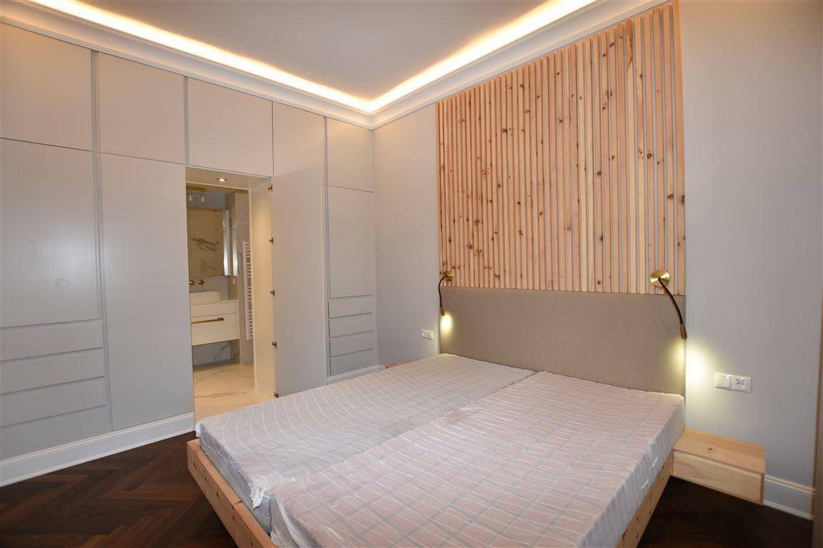 Schlafzimmer mit integrierten Kleiderschränken, Holzwandpaneel und Zugang zum Badezimmer.