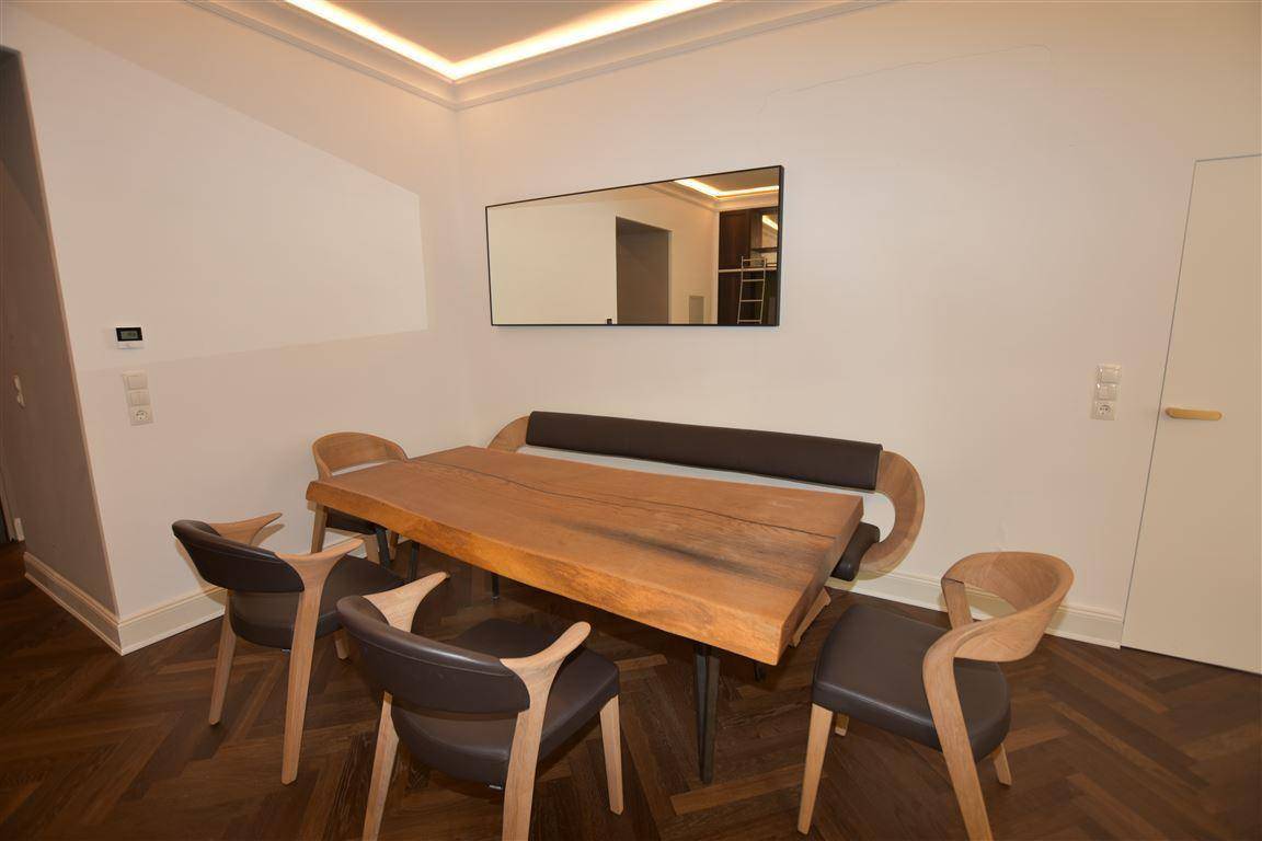 Detailansicht des Essbereichs mit rustikalem Holztisch und modernen Stühlen.