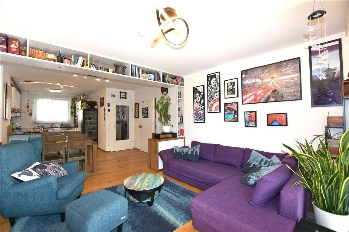 Offener Wohn- und Essbereich mit Bücherregalen, lila Sofa und Holzboden.